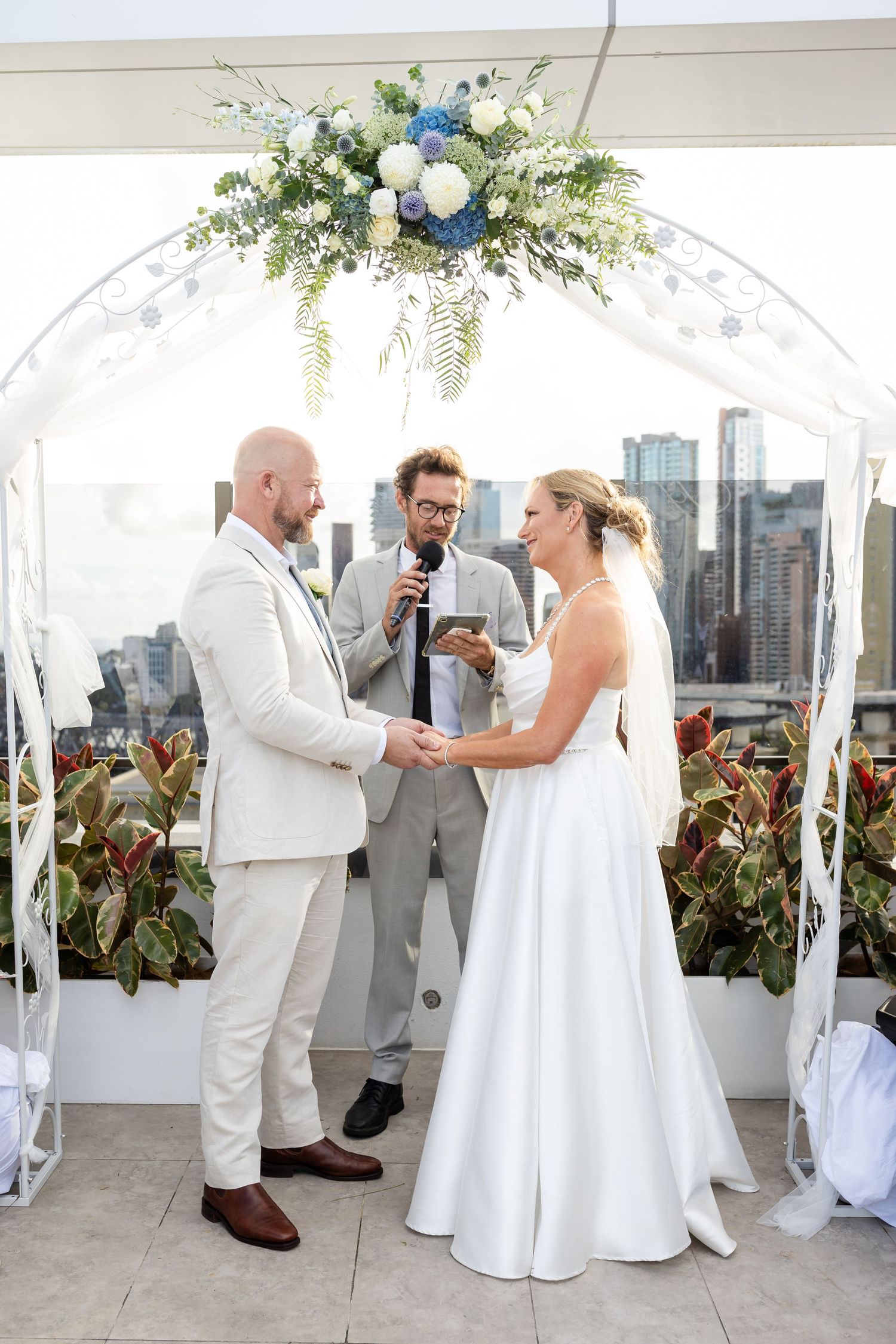 Wedding ceremony moments captured under a white arch with city views and elegant decor.