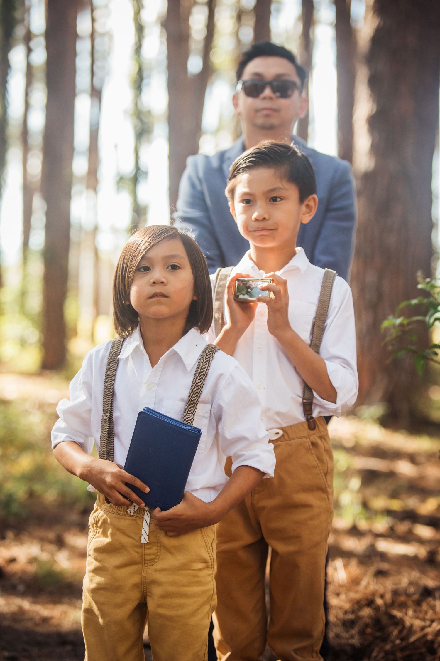 Young ring bearers in white shirts and khaki pants standing in a forest setting.pizzey park wedding Gold Coast