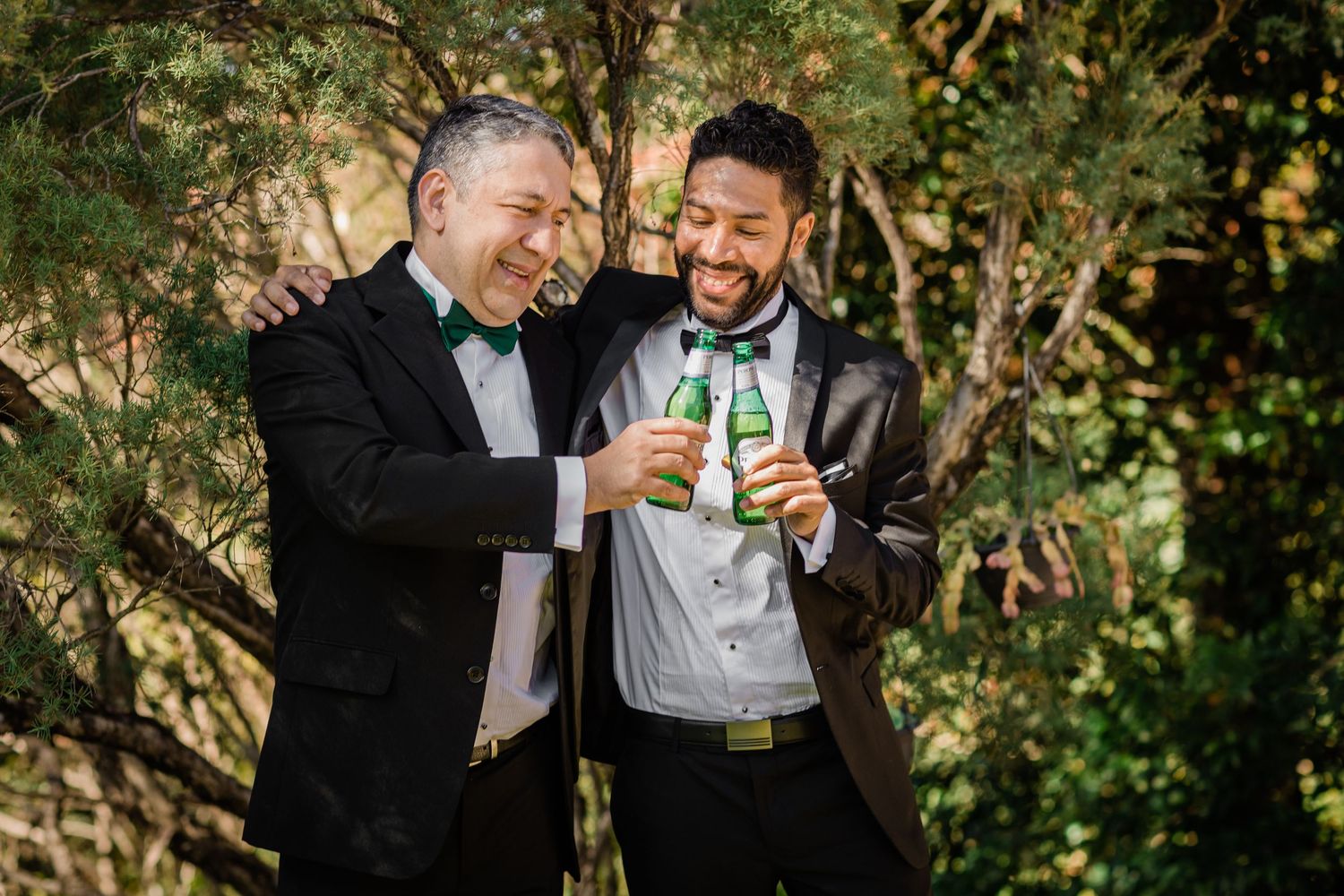 Two people in formal attire share drinks and laughter in an outdoor garden setting. Surfers Paradise Golf Club wedding.
