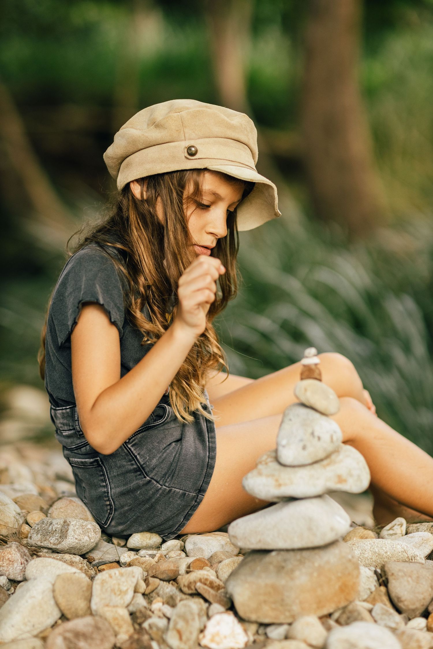 Person in a beige cap stacks stones carefully along a rocky surface in nature.Gold Coast family photographerGold Coast candid family photogr