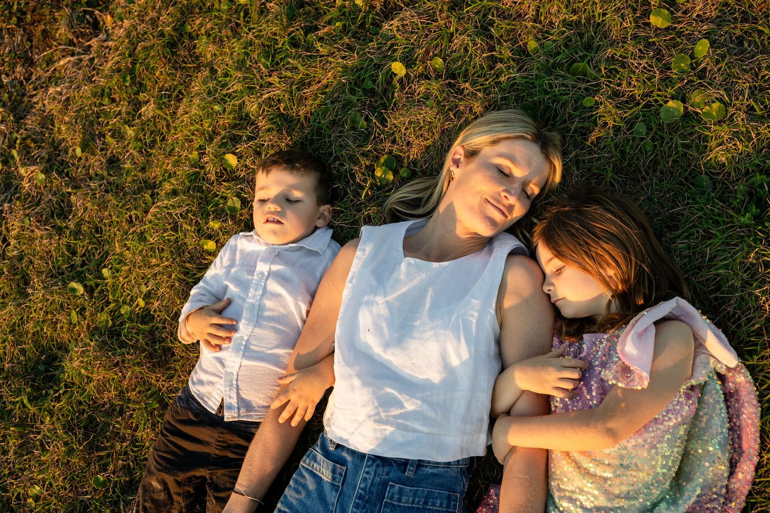Family enjoying a playful moment together in a golden-lit outdoor setting.Gold Coast candid family photographer. Cabarita headland