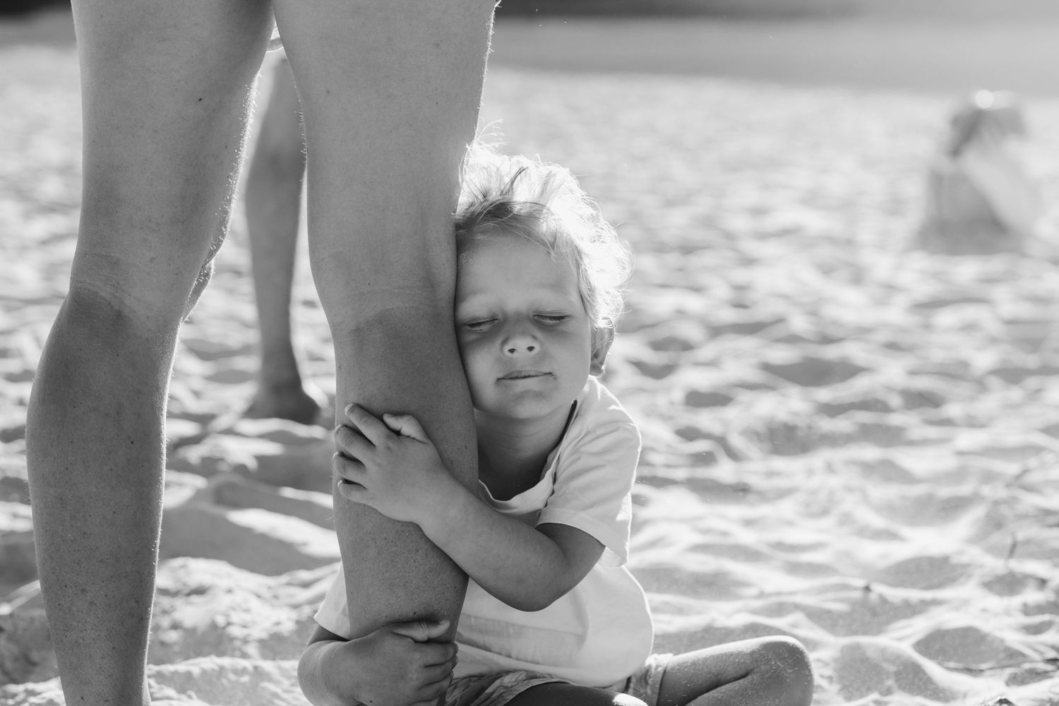 A black and white photo showing a tender moment between two people walking on a beach.Gold Coast candid family photographer.