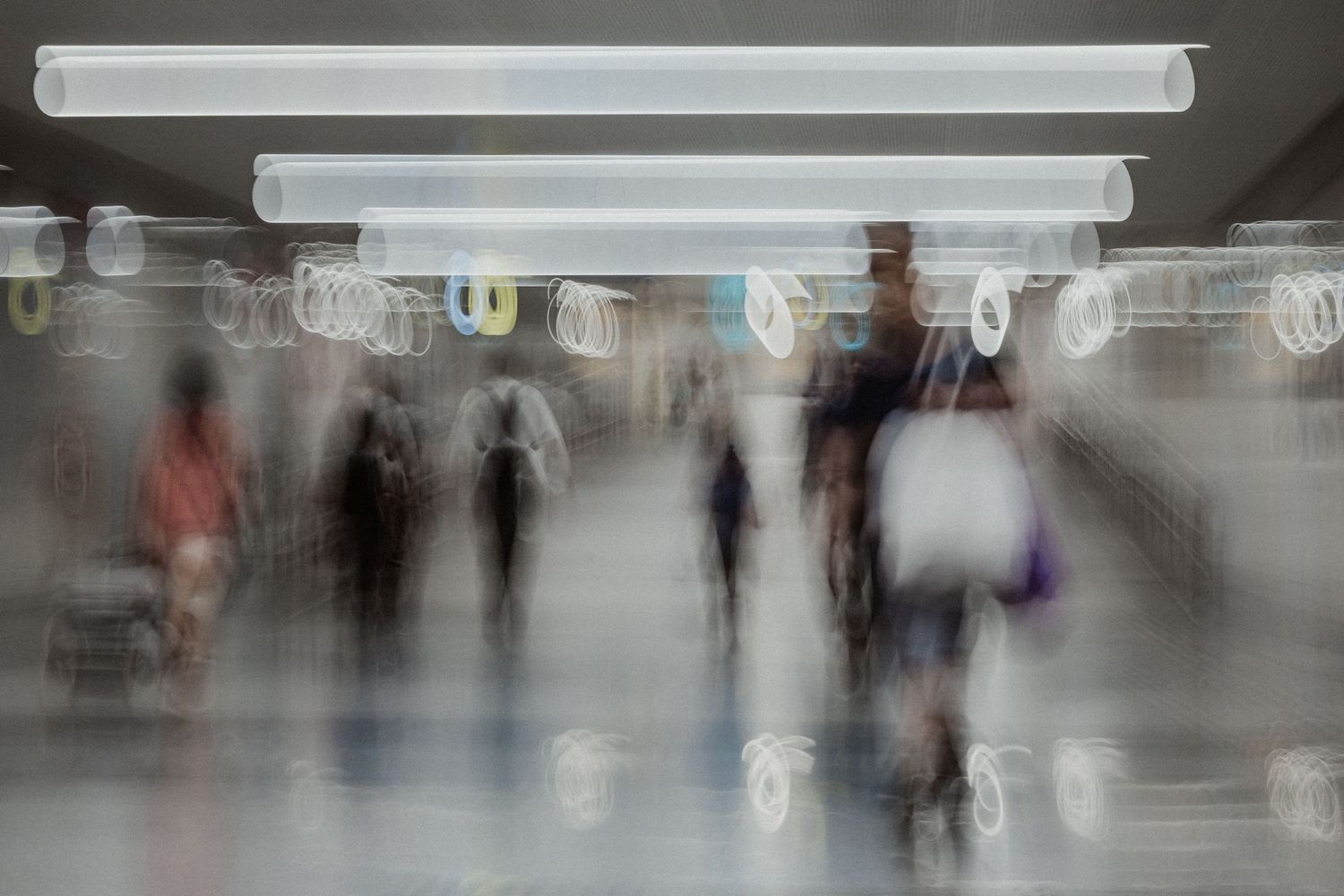 Blurred crowd of people moving through bright public space.