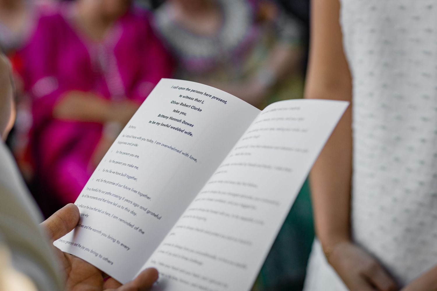 Wedding program booklets held by guests during the ceremony.