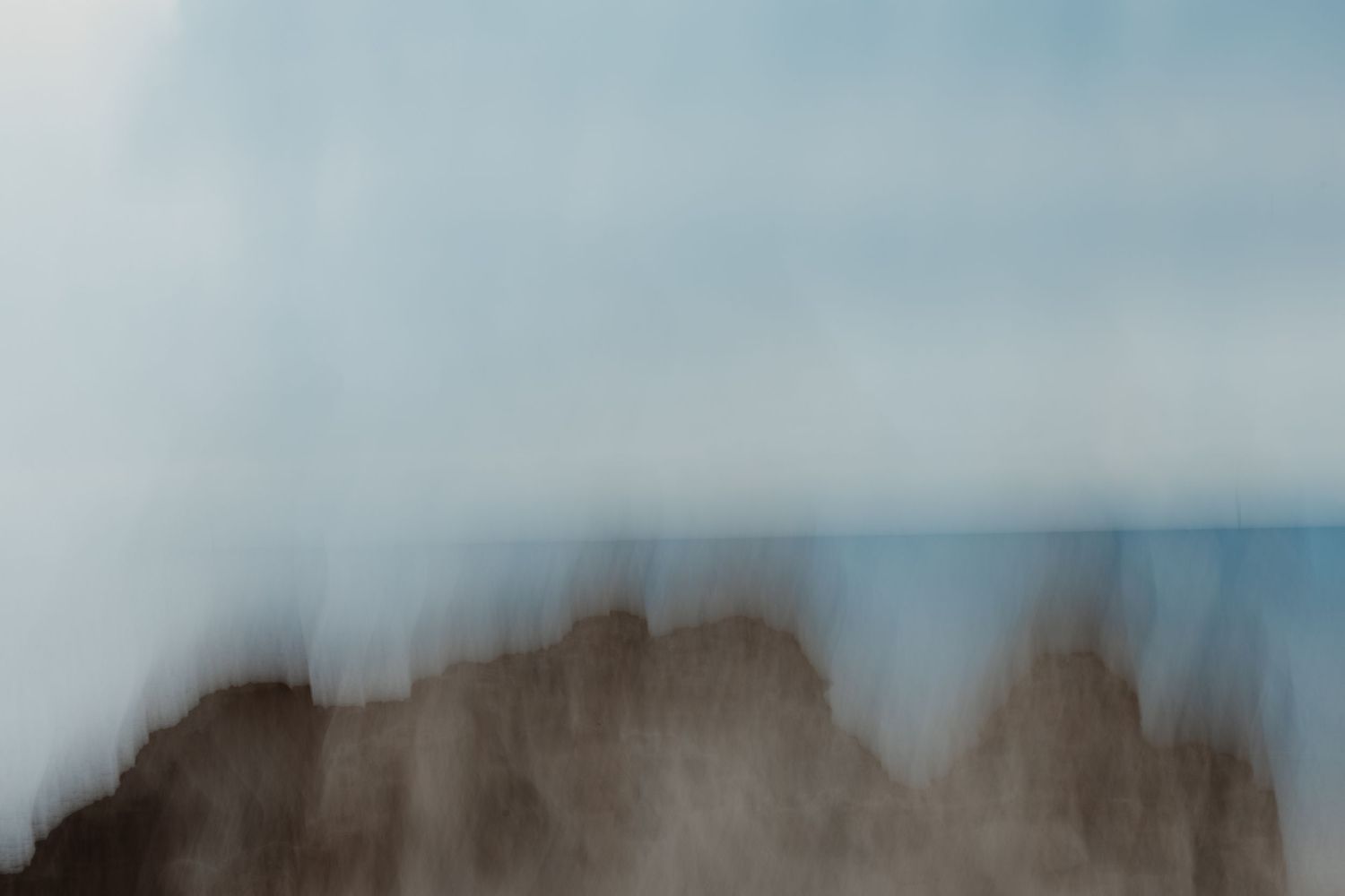 Minimalist landscape with soft blue sky fading into blurred mountains.