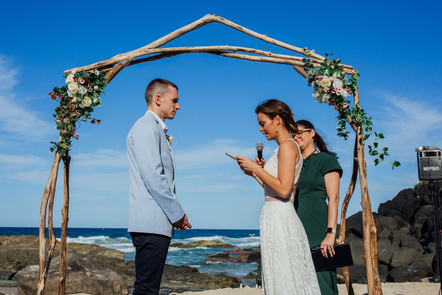 Beach wedding ceremony setup with driftwood arch aGold Coast beach wedding photography. Froggies beachgainst blue ocean backdrop.
