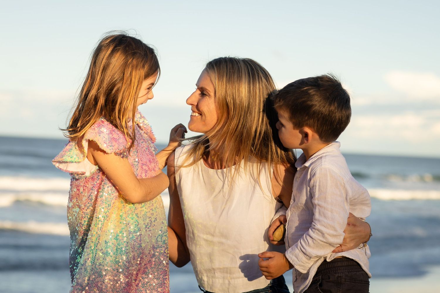 A joyful family embracing and laughing together on a sunny beach.Family photography cabarita New South Wales Cabarita headland