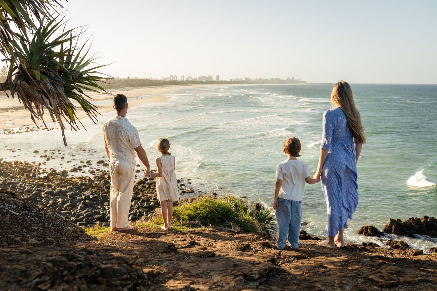 Scenic coastal view with palm trees and ocean waves breaking on shore. Gold Coast candid family photographer.