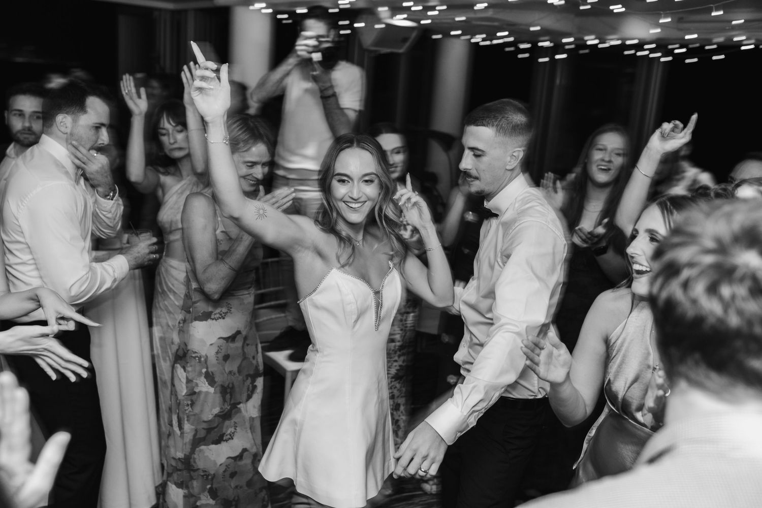Black and white photo of wedding guests dancing enthusiastically on the dance floor.beach wedding currumbin surf club wedding