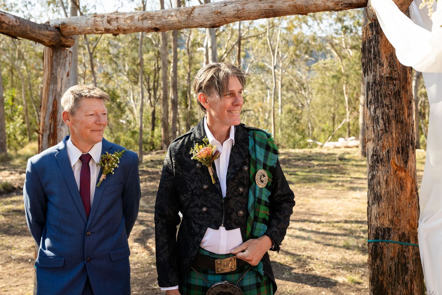 Wedding ceremony guests seated on wooden benches in a natural outdoor setting.