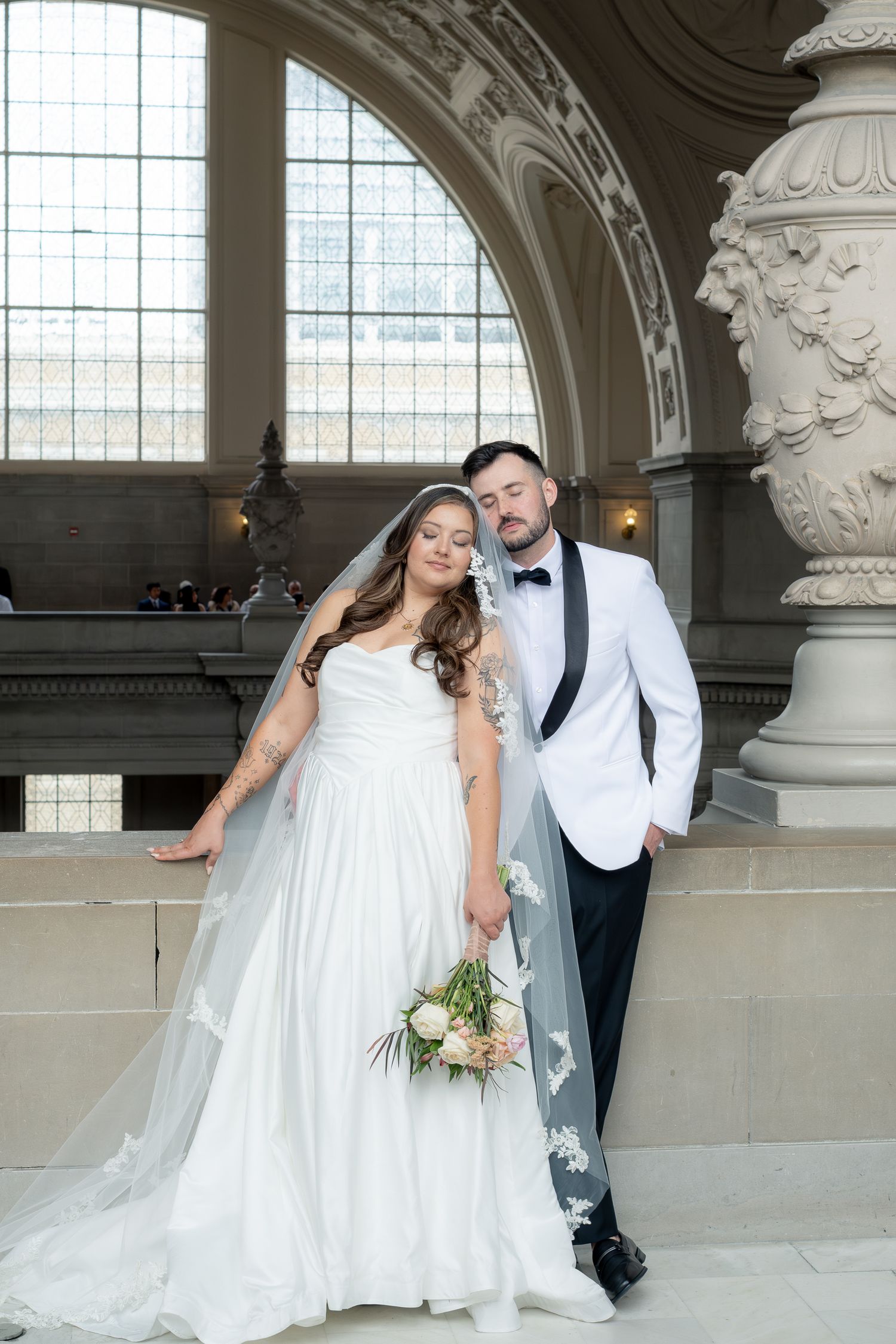 Bride and groom pose together beneath a stained glass arch at San Francisco City Hall.