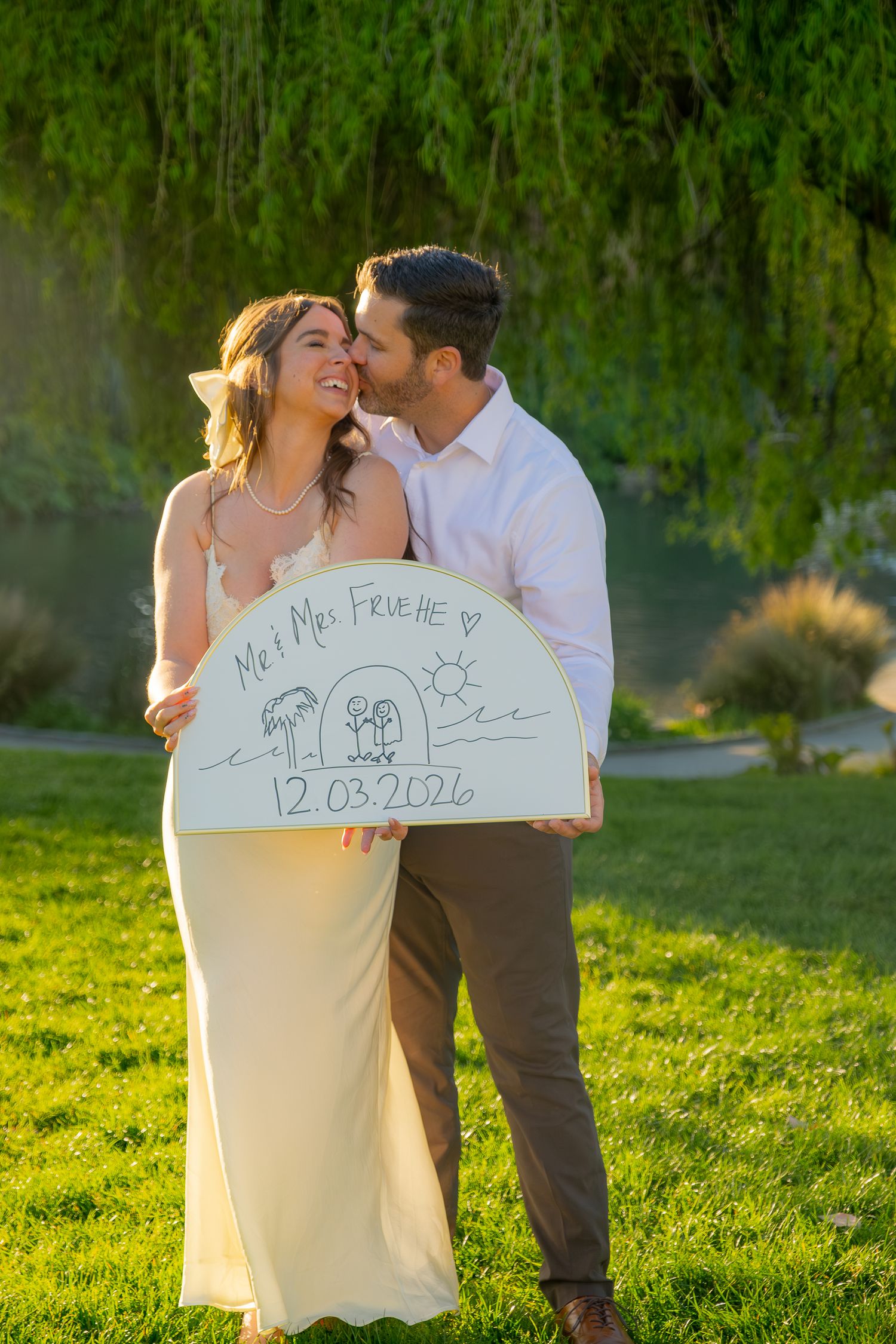 Happy couple holding a sign reading Mr & Mrs Fruette with wedding date 12.03.2026 outdoors.