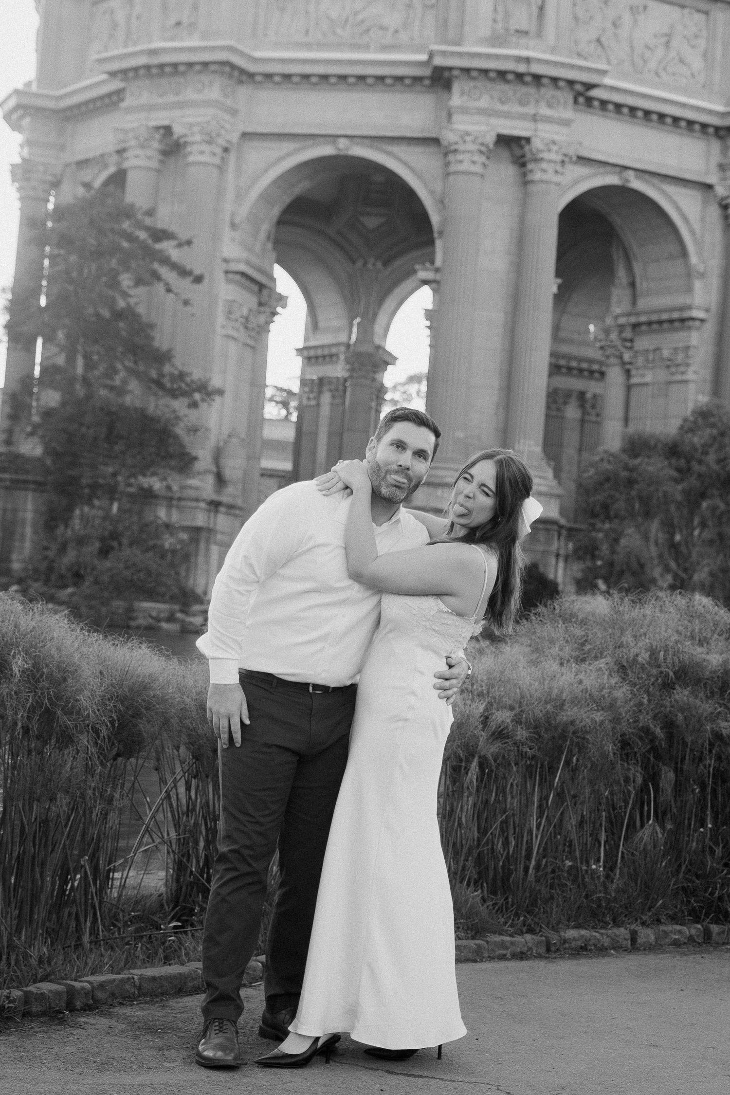 Black and white photo of a couple embracing in front of the Palace of Fine Arts in San Francisco.