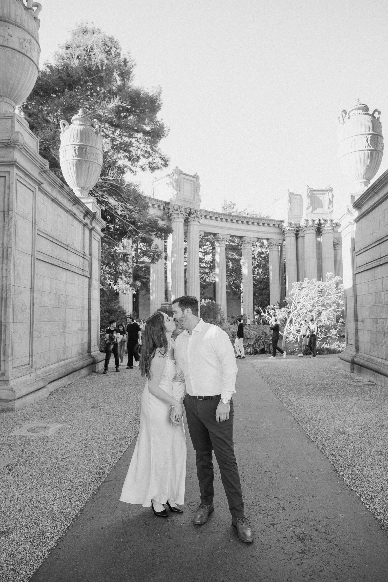 Black and white photo of a couple sharing a romantic moment at the Palace of Fine Arts in San Francisco.