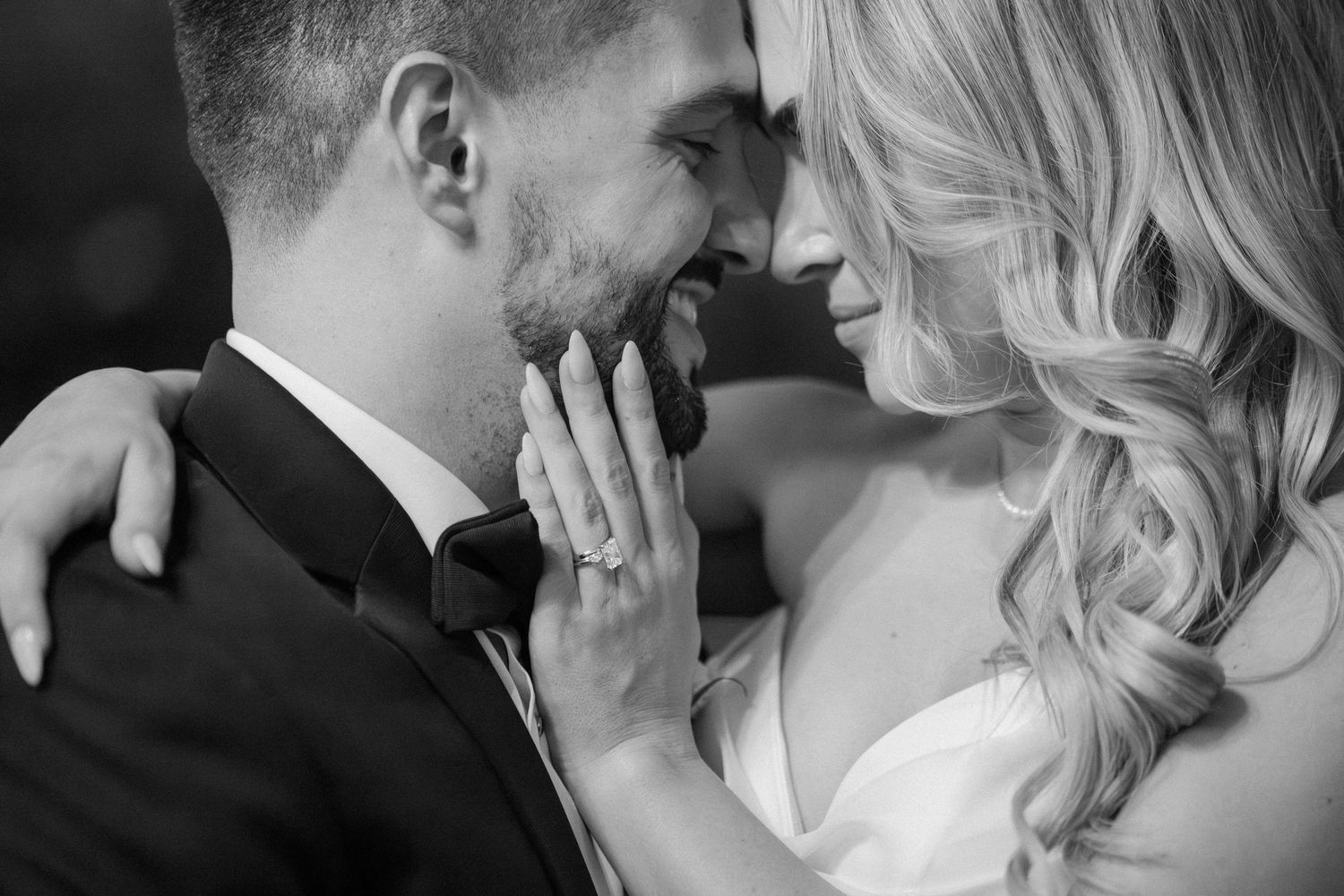 Black and white close-up of bride and groom sharing an intimate moment, bride wearing diamond engagement ring.