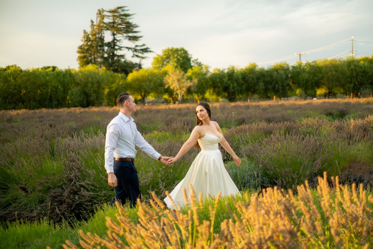 Couple holding hands walking through a lavender field at sunset.