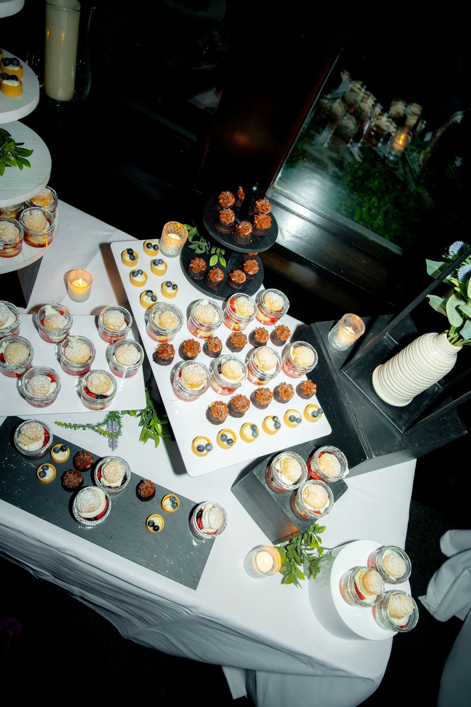 Elegant wedding dessert table displays assorted mini treats, cupcakes, and bite-sized sweets on tiered stands.