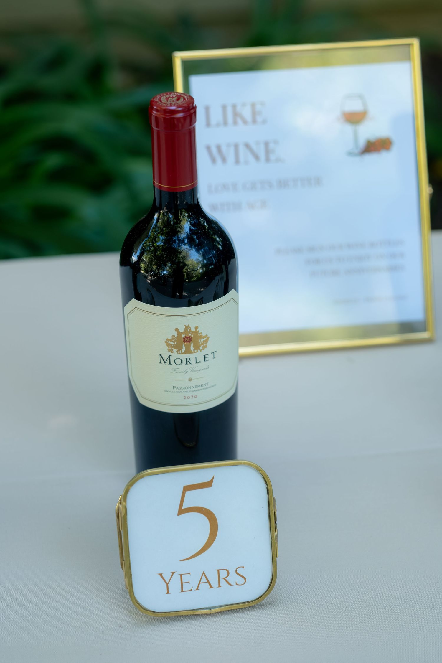 Morlet red wine bottle beside a gold-framed 5 Years anniversary sign with a wine quote backdrop.