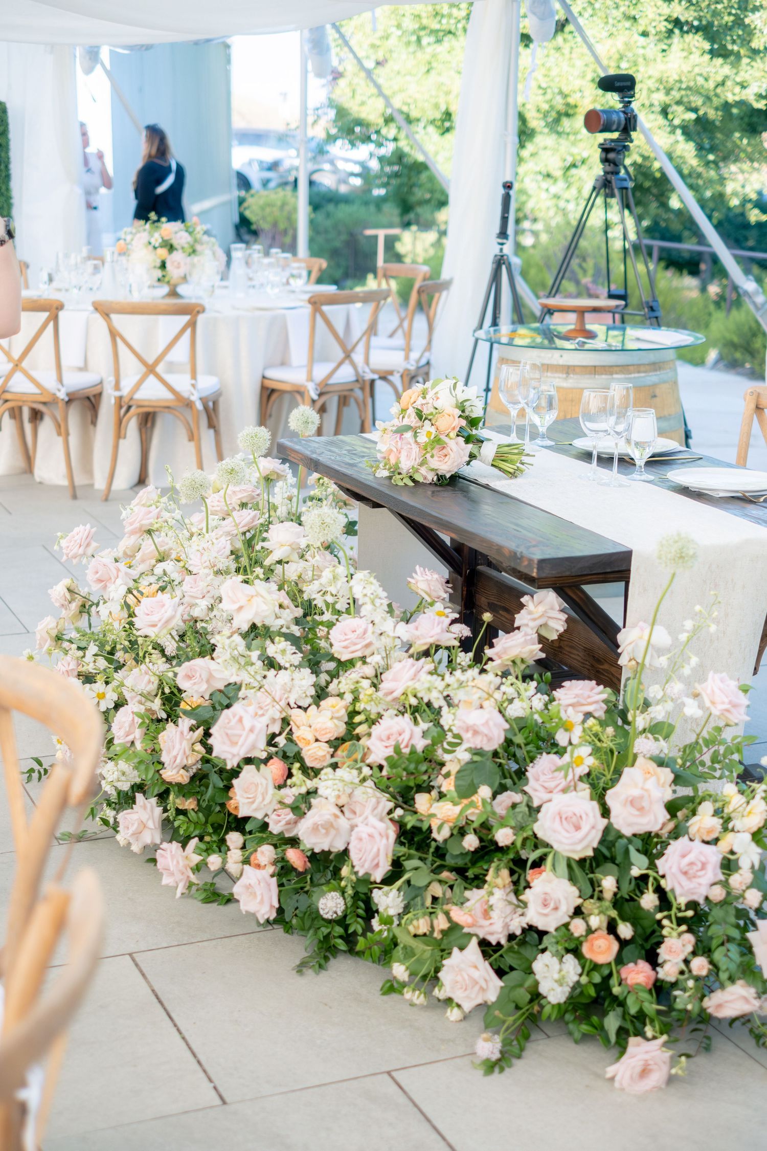 Elegant wedding reception table adorned with lush pink and white floral arrangements under a tent.