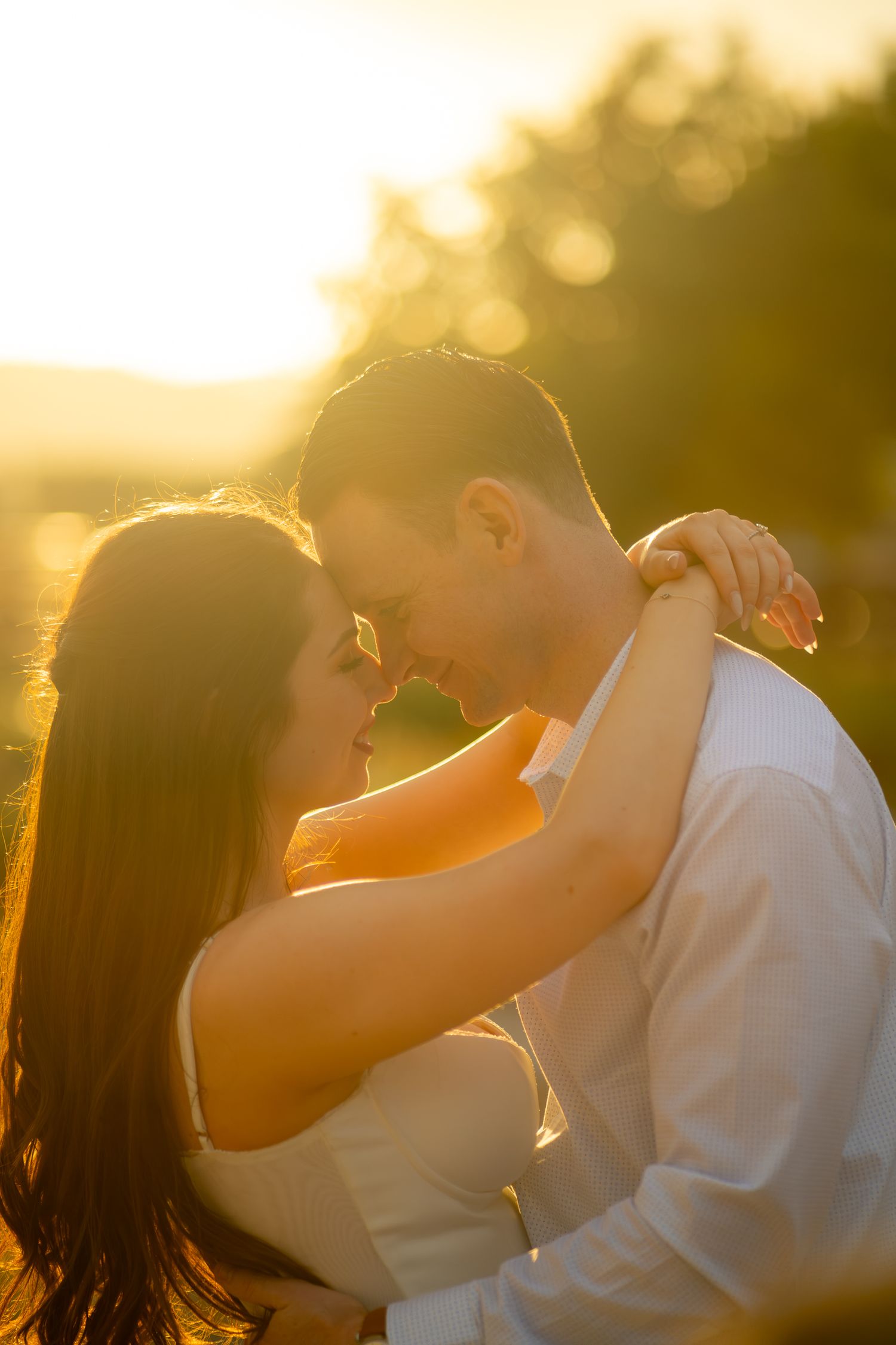 Romantic couple nearly kissing bathed in warm golden sunset light.