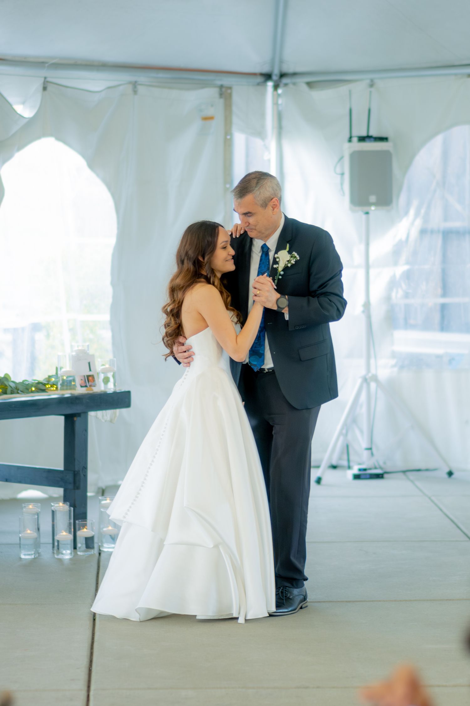 Bride and groom share first dance under white tent at elegant wedding reception.