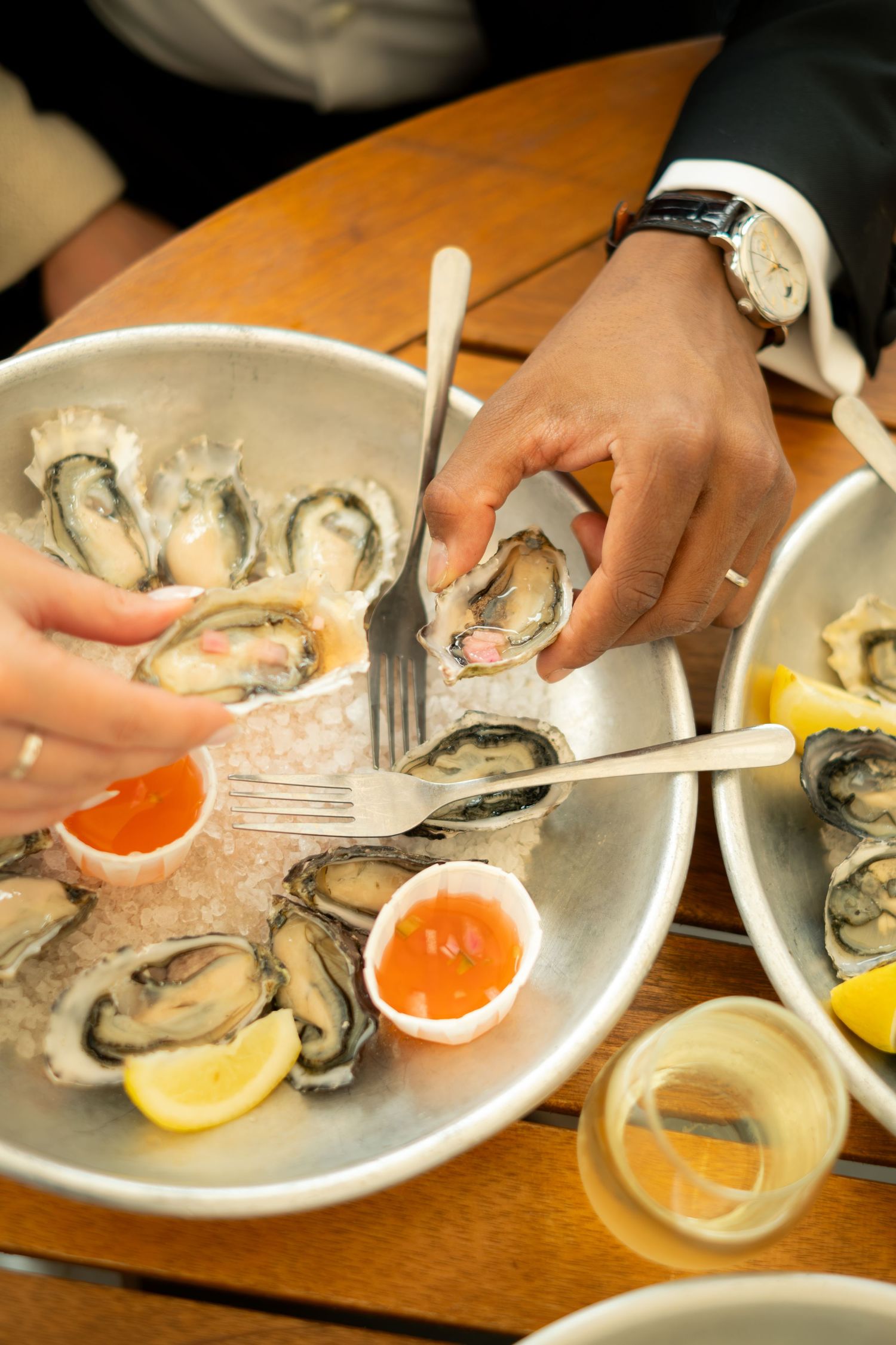 Close-up of a couple sharing fresh oysters on ice with cocktail sauce at a wedding dinner.