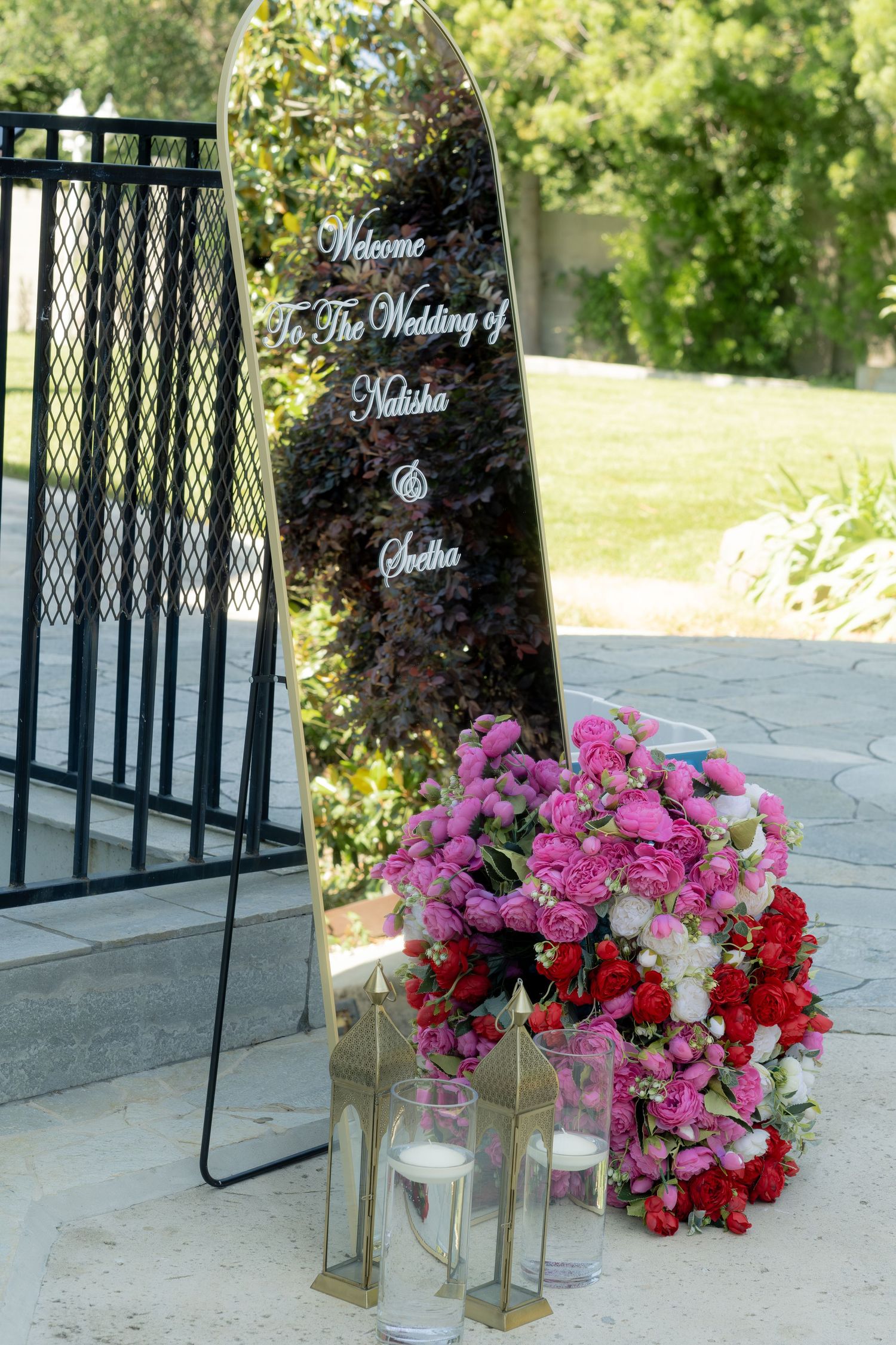 Elegant mirrored wedding welcome sign for Natisha and Seetha adorned with pink floral arrangements.