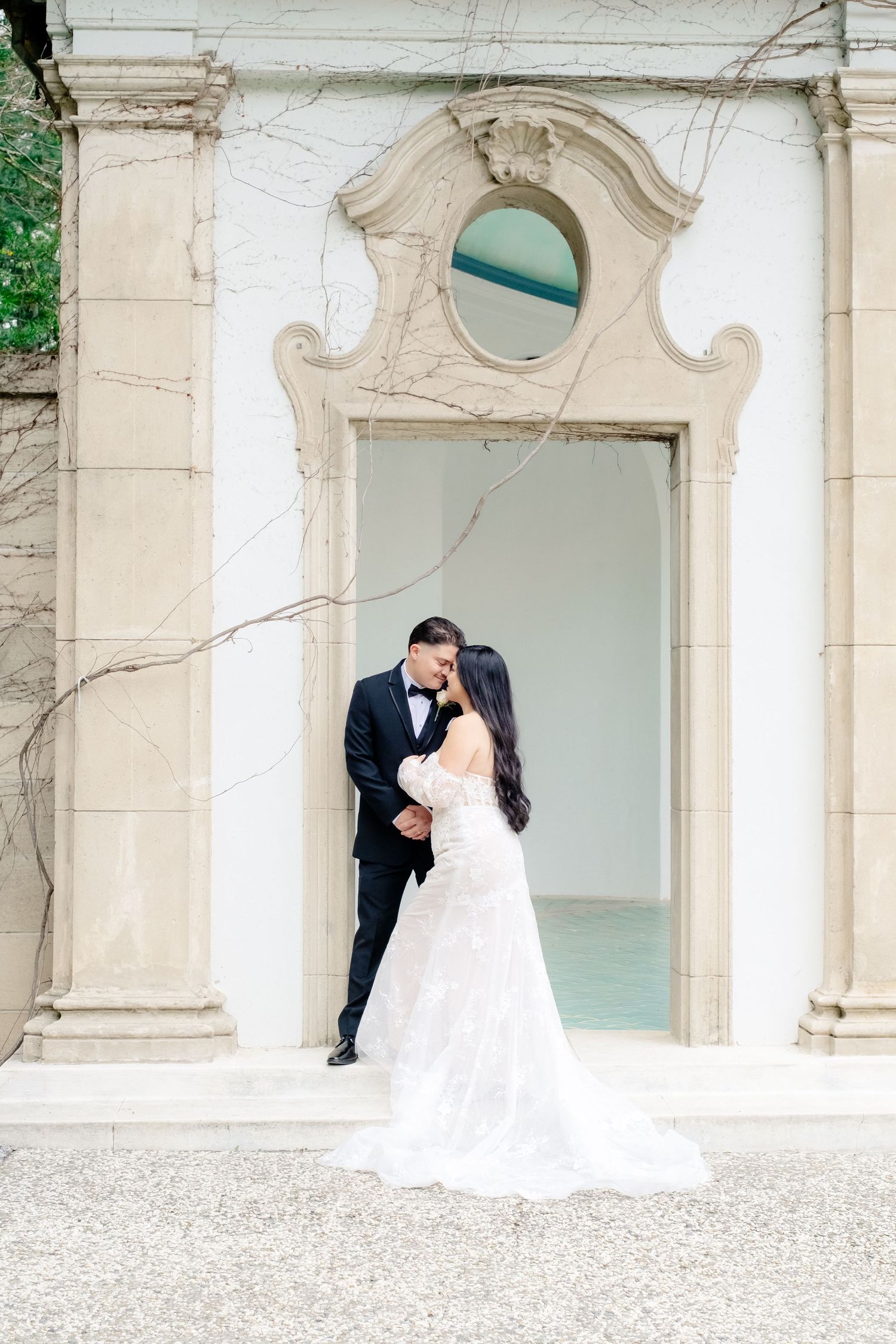 Bride and groom sharing a romantic kiss in front of elegant ornate architectural doorway outdoors.