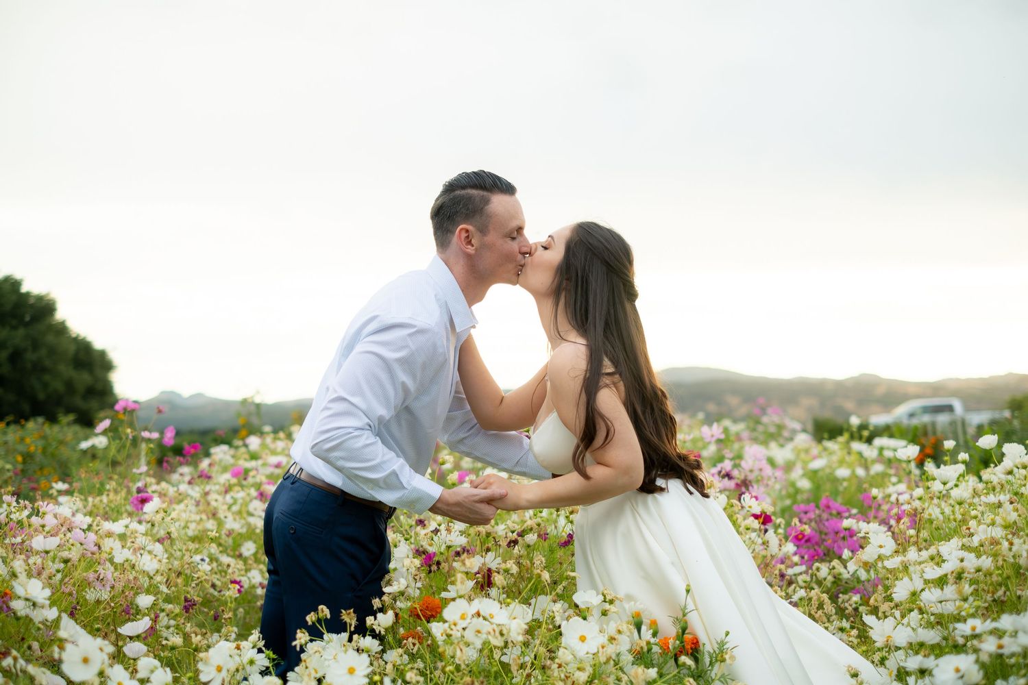 Couple kissing in a blooming flower field during golden hour for their engagement photos.
