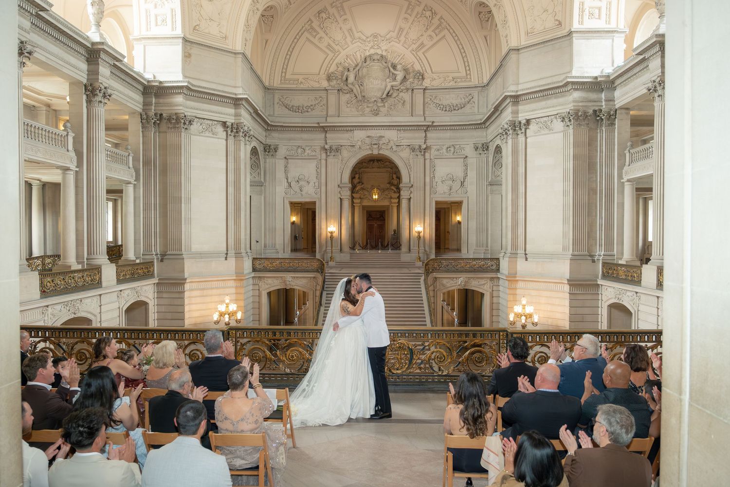Bride and groom share a kiss at the altar during an elegant wedding ceremony inside San Francisco City Hall.