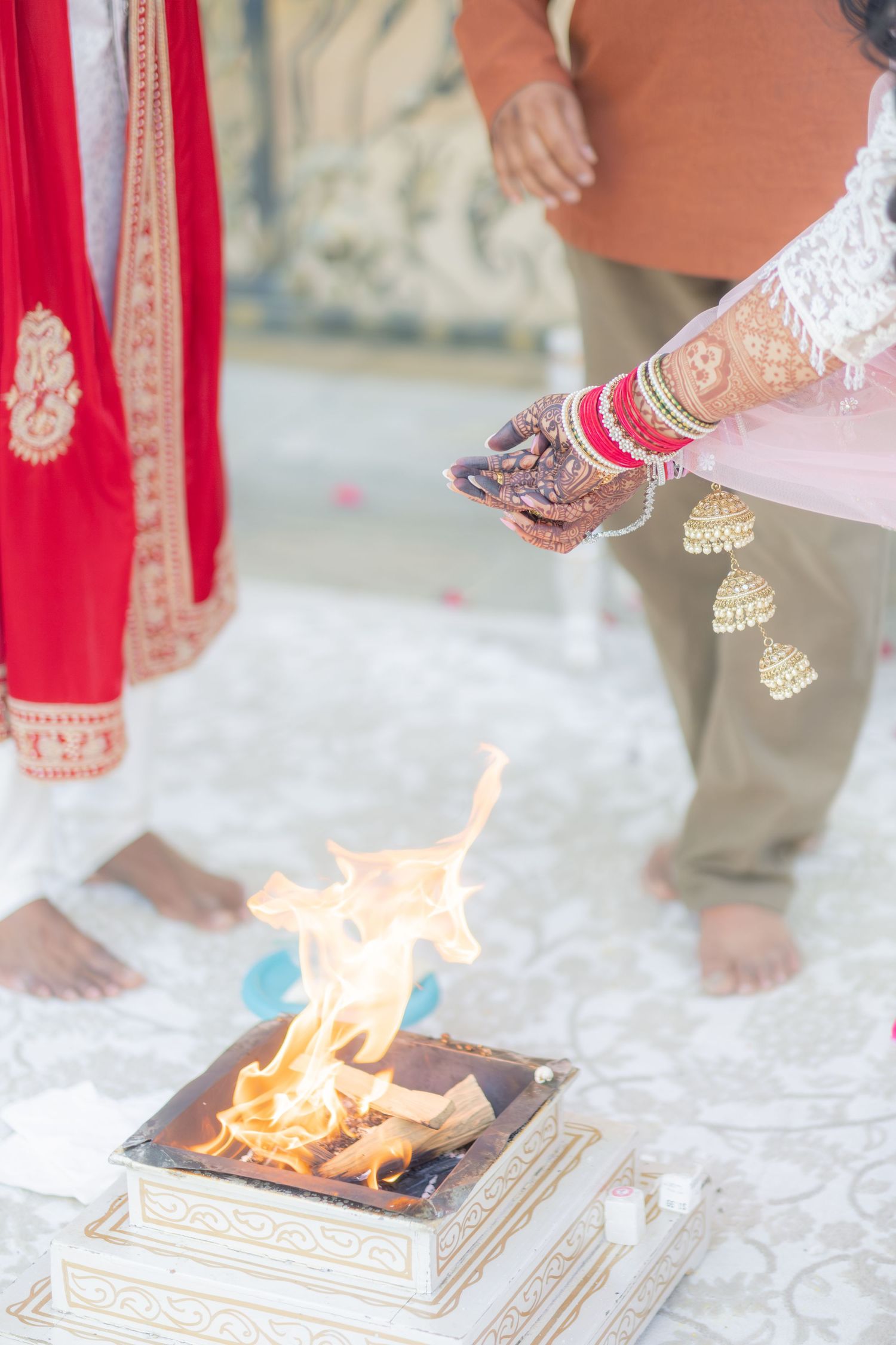Close-up of bride's henna hands performing sacred Hindu fire ritual during traditional wedding ceremony.