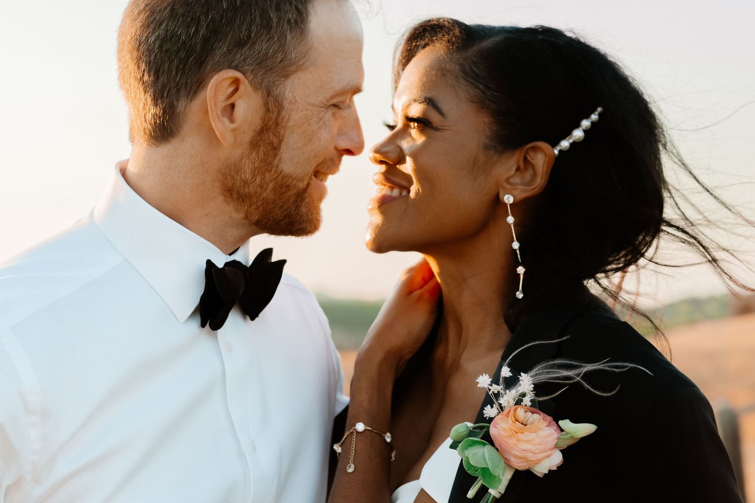 Interracial couple sharing a romantic moment at golden hour wedding outdoors.