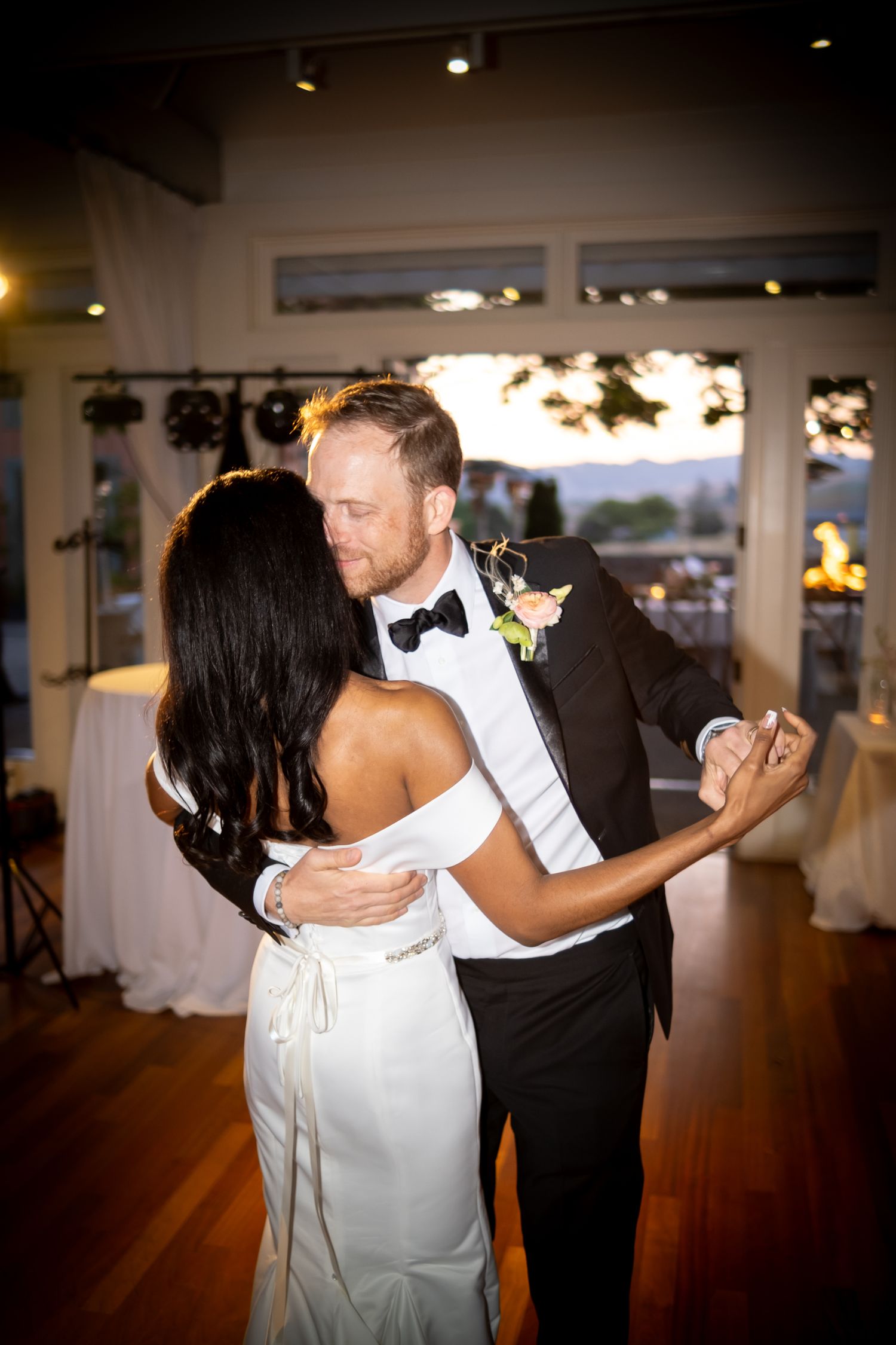 Newlyweds sharing their first dance in a warmly lit wedding reception venue.