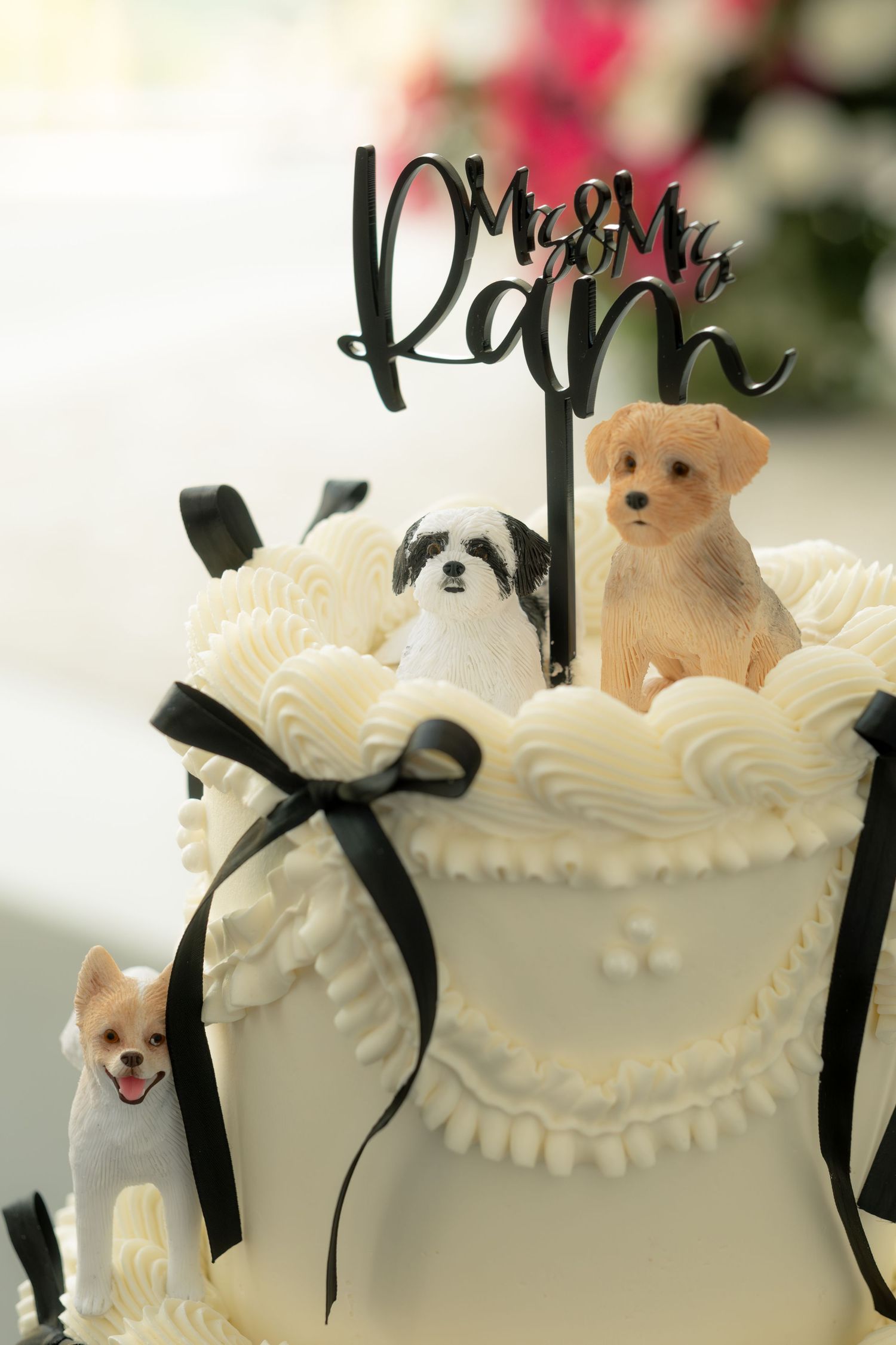Elegant white wedding cake with dog figurines and Mrs and Mr Ram cake topper with black ribbon.