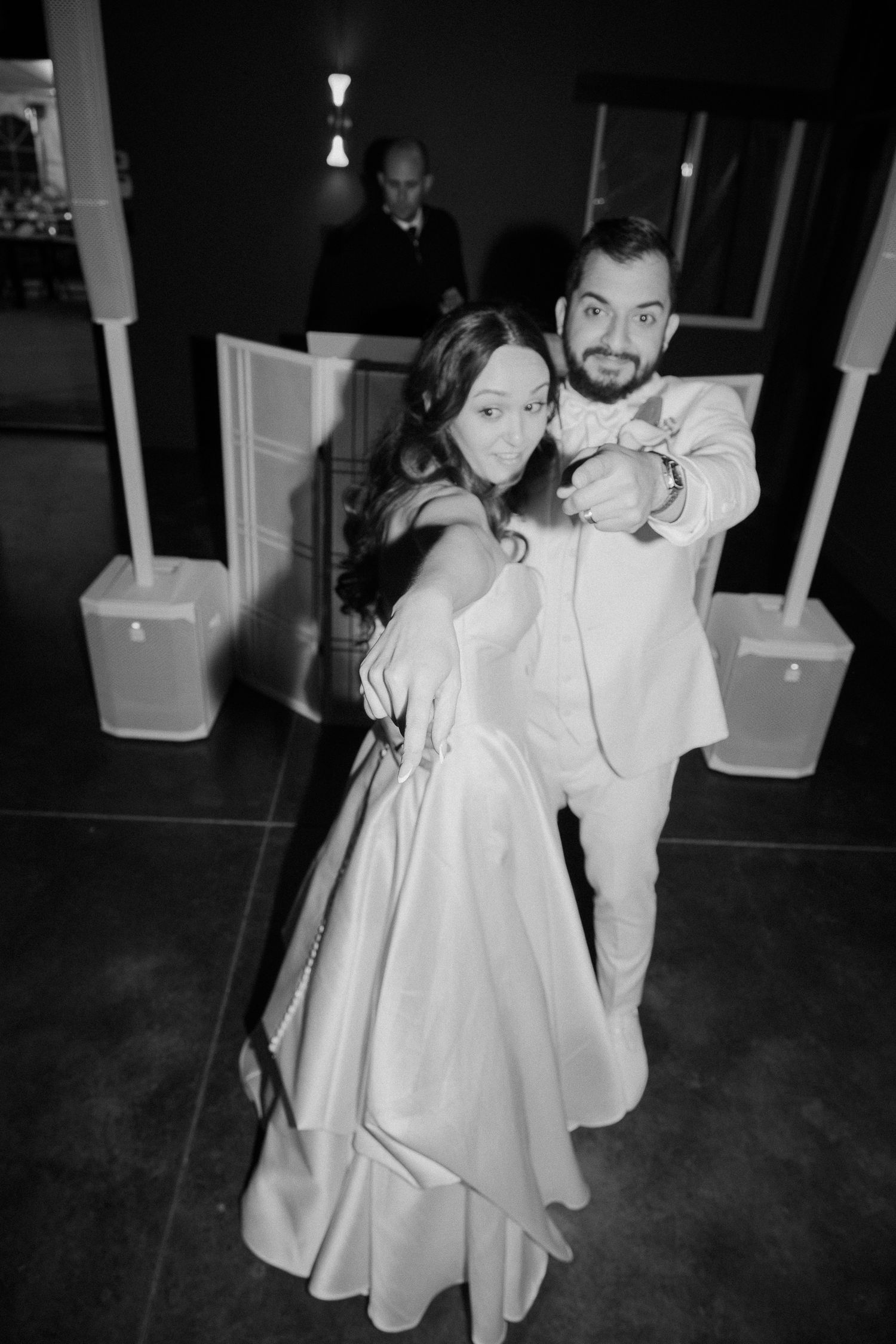 Bride and groom pose playfully on the dance floor during their first dance at wedding reception.