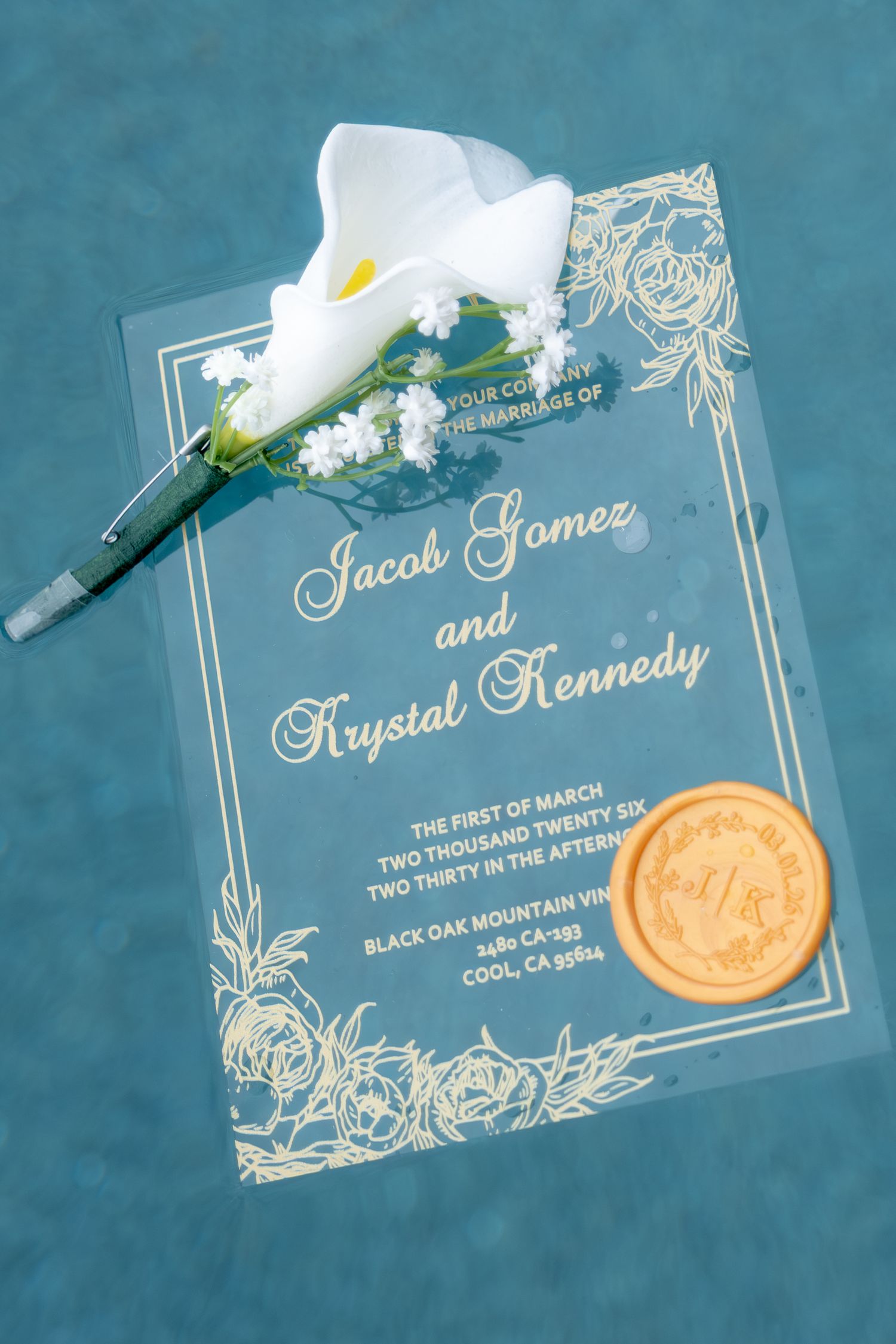 Elegant acrylic wedding invitation for Jacob Gomez and Krystal Kennedy with gold wax seal and white calla lily boutonniere.