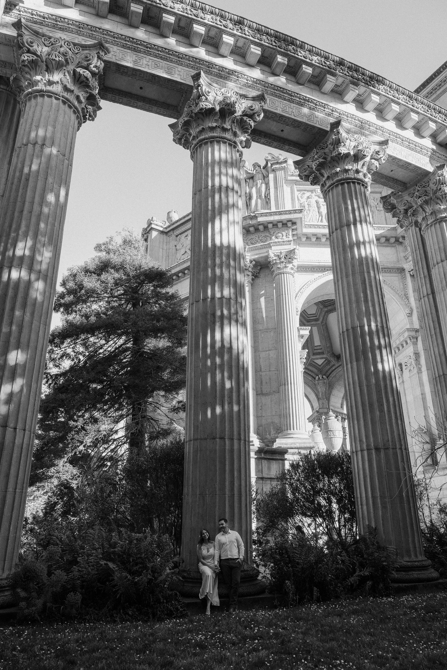 Black and white photo of a couple standing among grand Corinthian columns at the Palace of Fine Arts, San Francisco.
