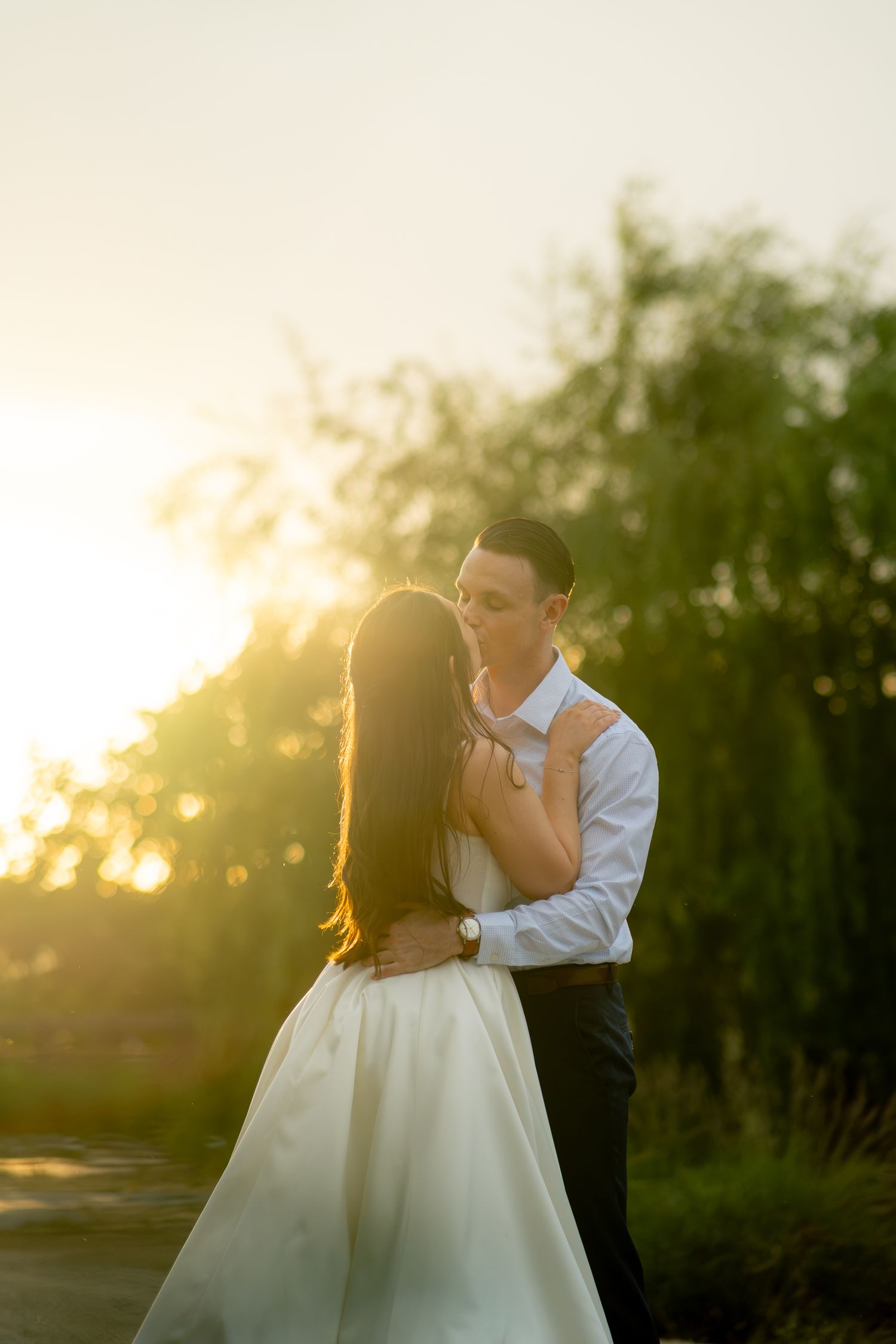 A couple shares a romantic kiss at golden hour during their wedding photo session.