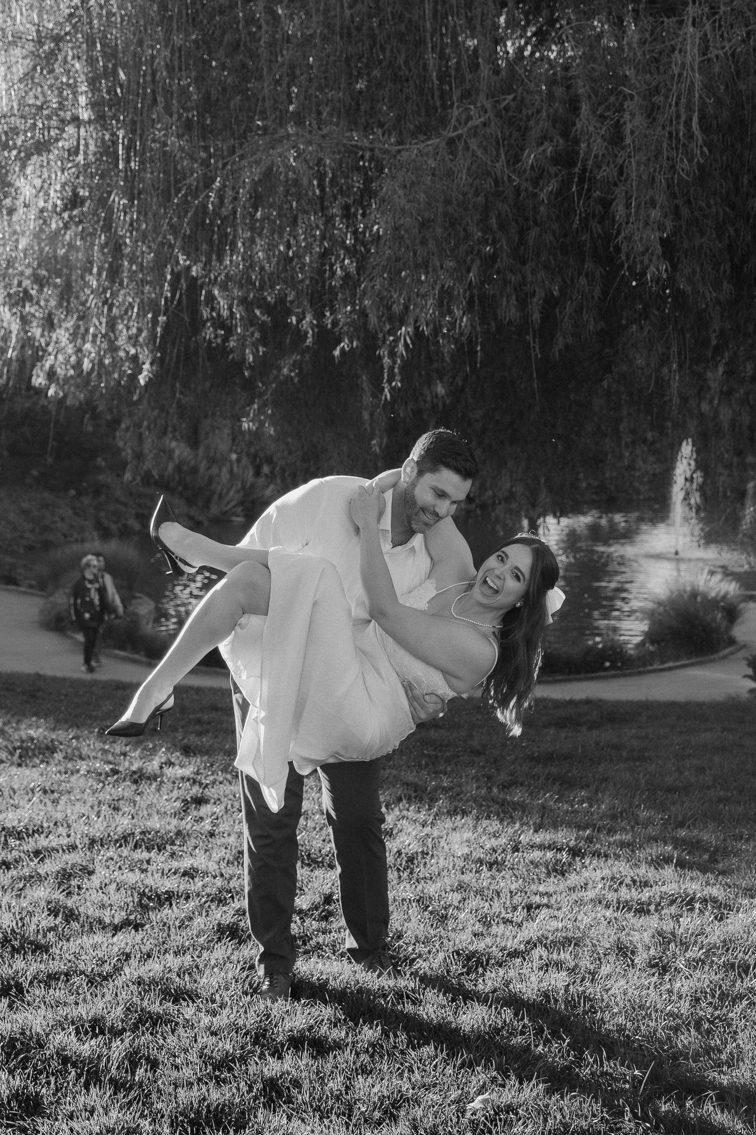 Groom playfully lifting his bride in a black and white outdoor engagement photo session.