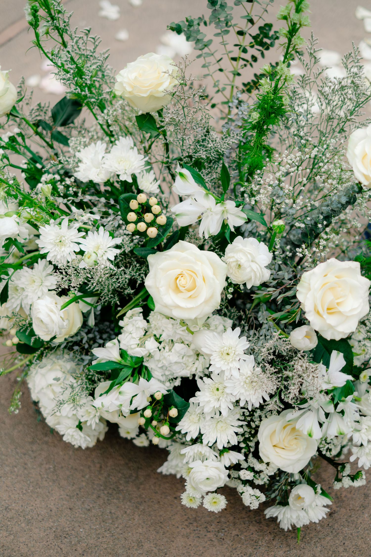 Elegant white rose and chrysanthemum wedding floral arrangement with greenery accents.