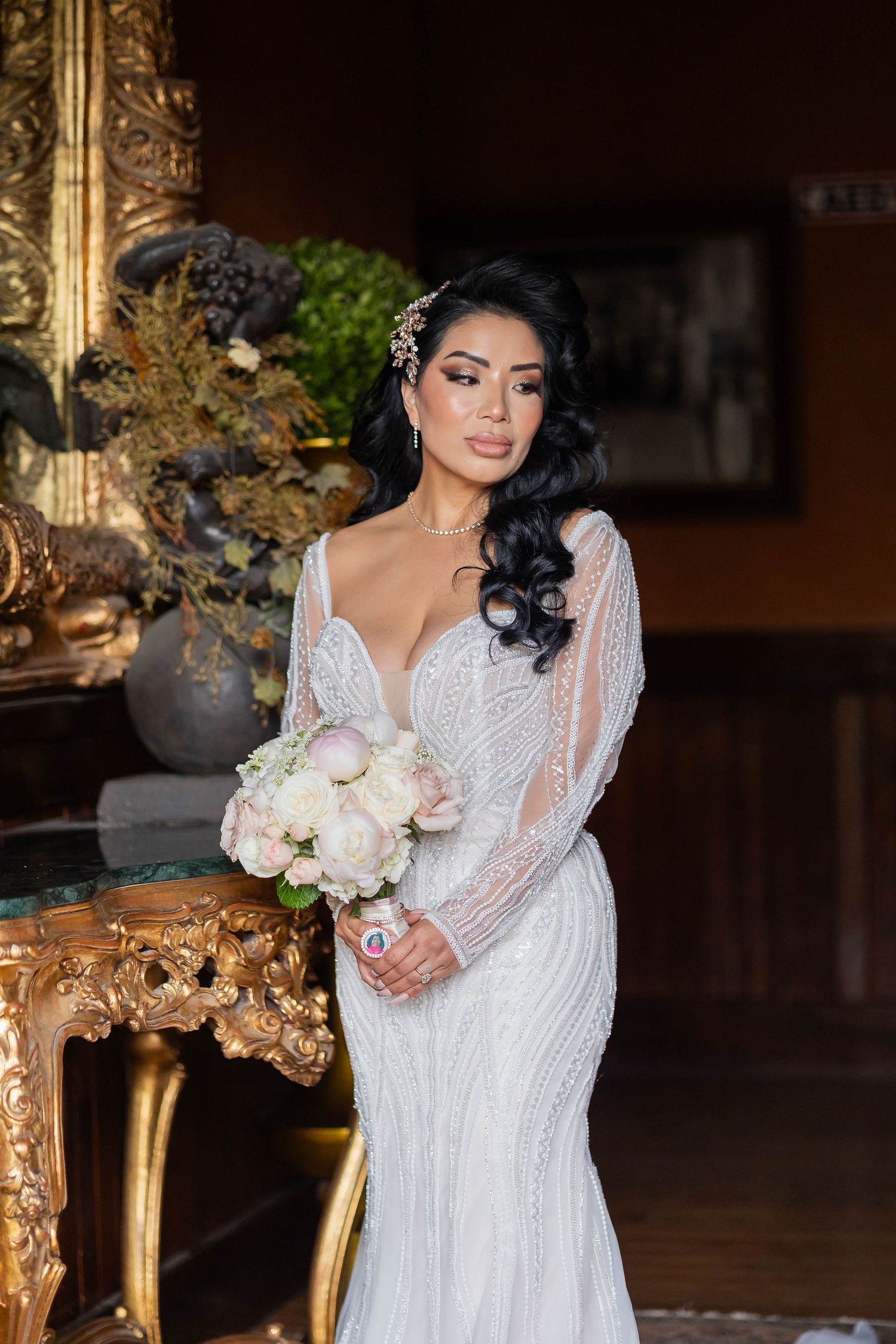 Beautiful bride in a beaded long sleeve mermaid wedding gown holding a white bouquet.