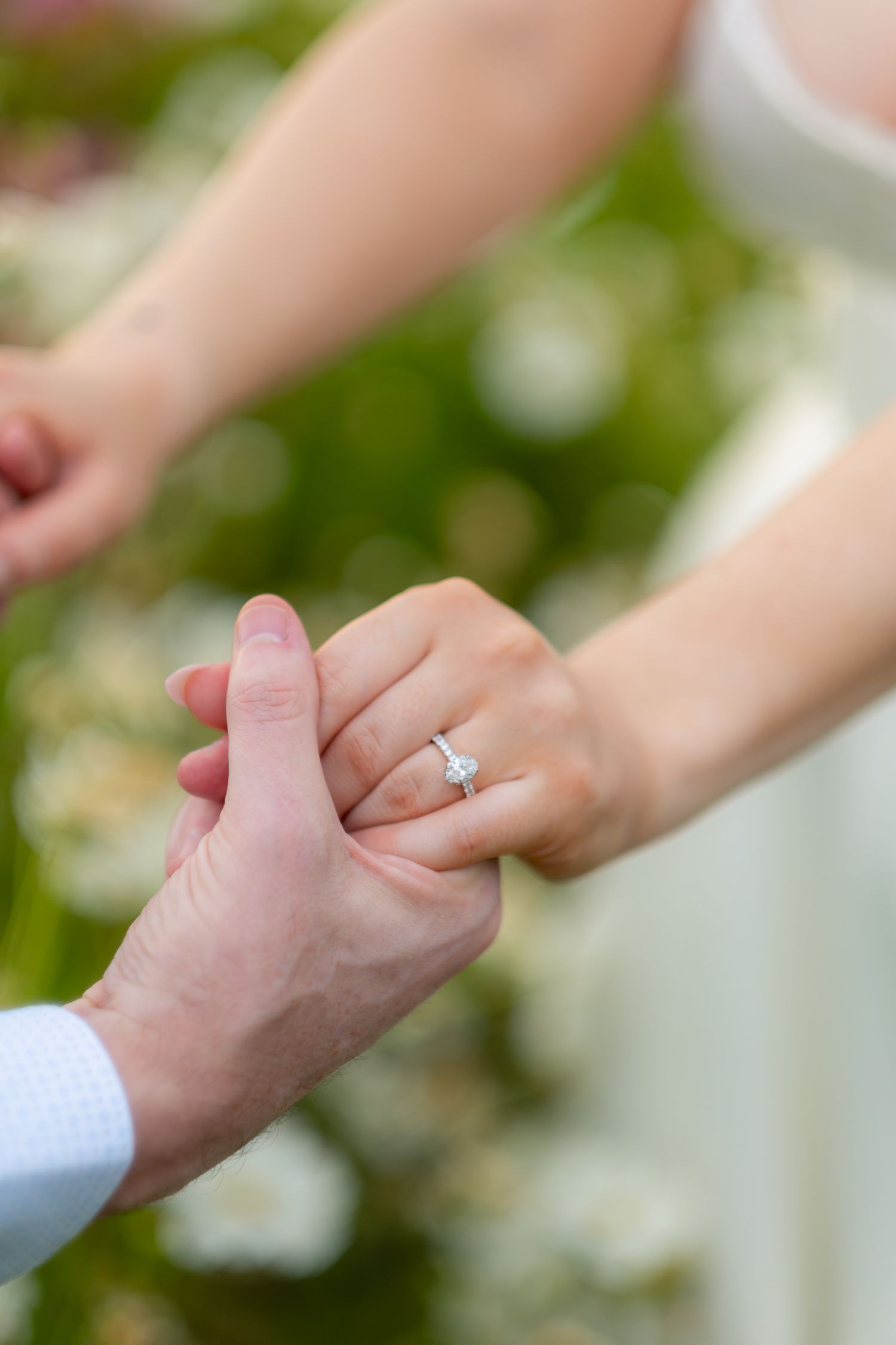 Close-up of a bride's hand holding her groom's, showcasing a diamond engagement ring.