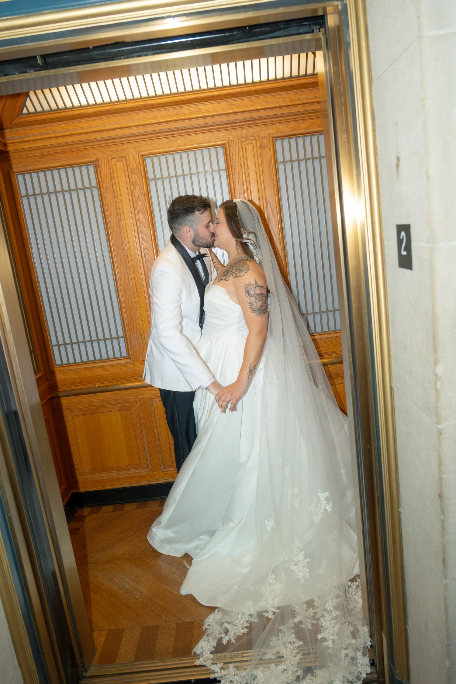 Bride and groom steal a kiss inside a vintage wood-paneled elevator at San Francisco City Hall.