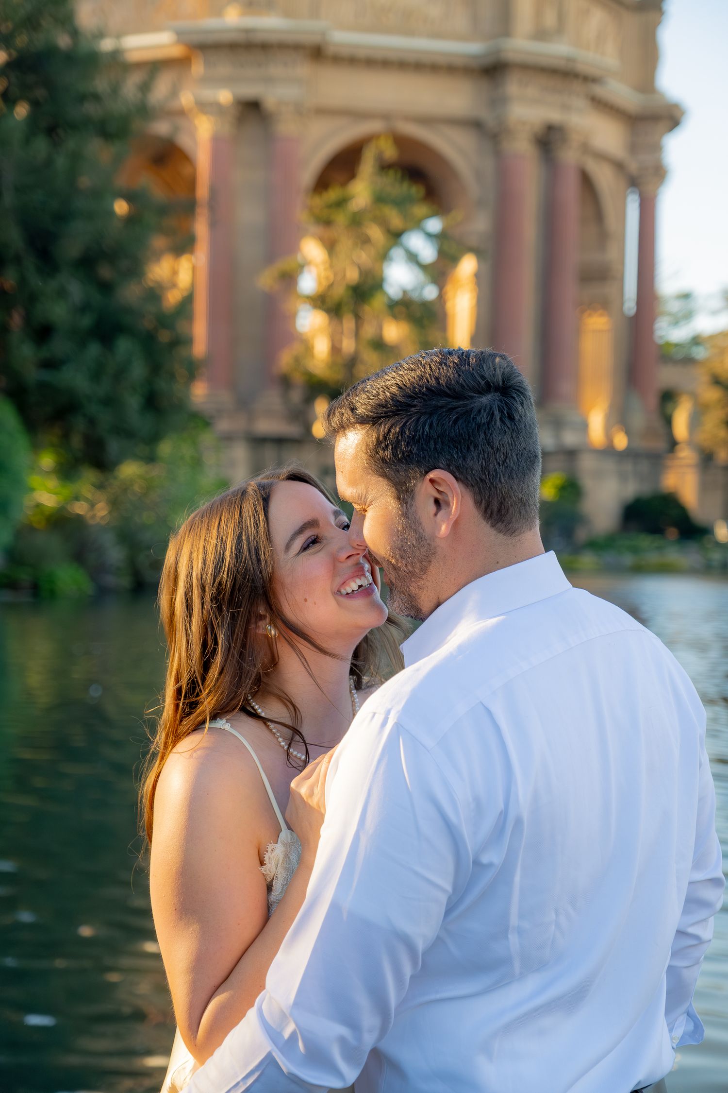 Romantic couple sharing a tender moment near a reflective pond at the Palace of Fine Arts.