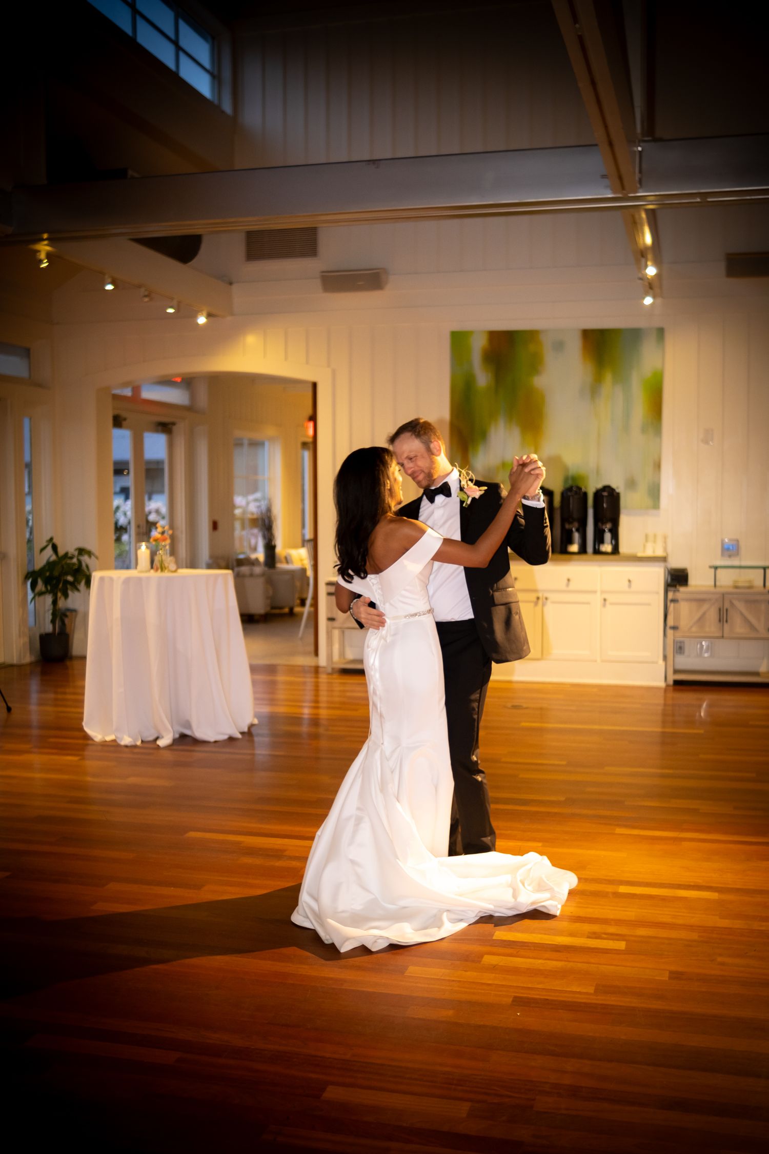 Bride and groom dancing together on wooden dance floor at elegant wedding reception.