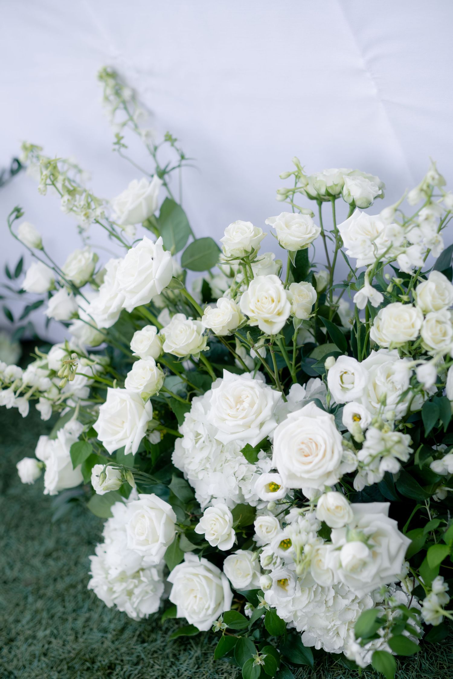 Lush arrangement of white roses, hydrangeas, and greenery for a classic wedding ceremony.