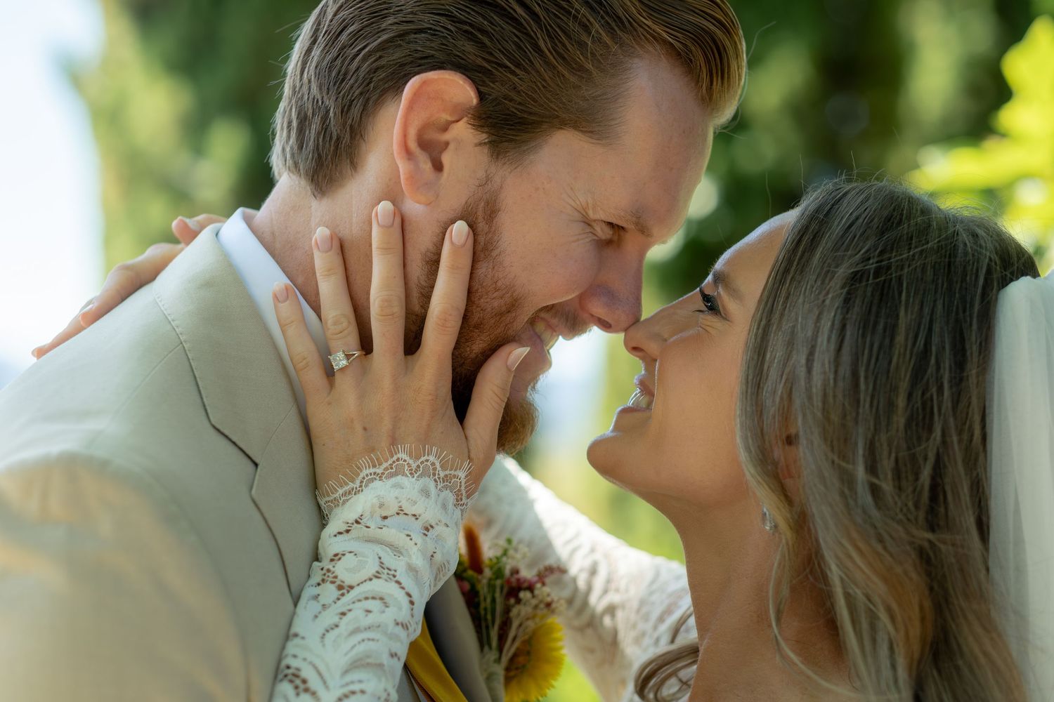 Bride and groom sharing an intimate moment, nearly kissing, with her hands gently cupping his face.