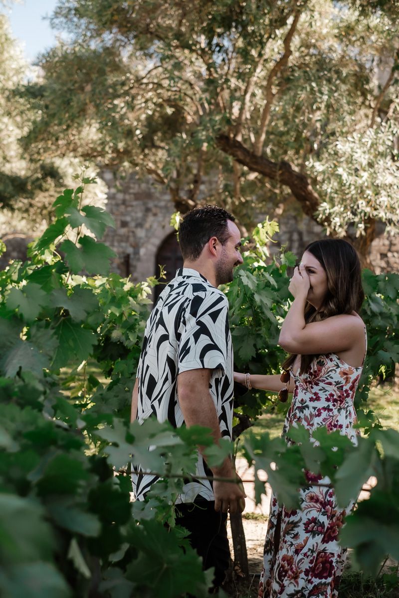 Romantic couple sharing a moment among lush green grapevines in a vineyard.