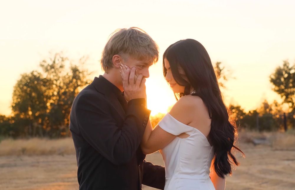 Emotional couple sharing an intimate moment at sunset in a golden field, groom tenderly touching bride's face.