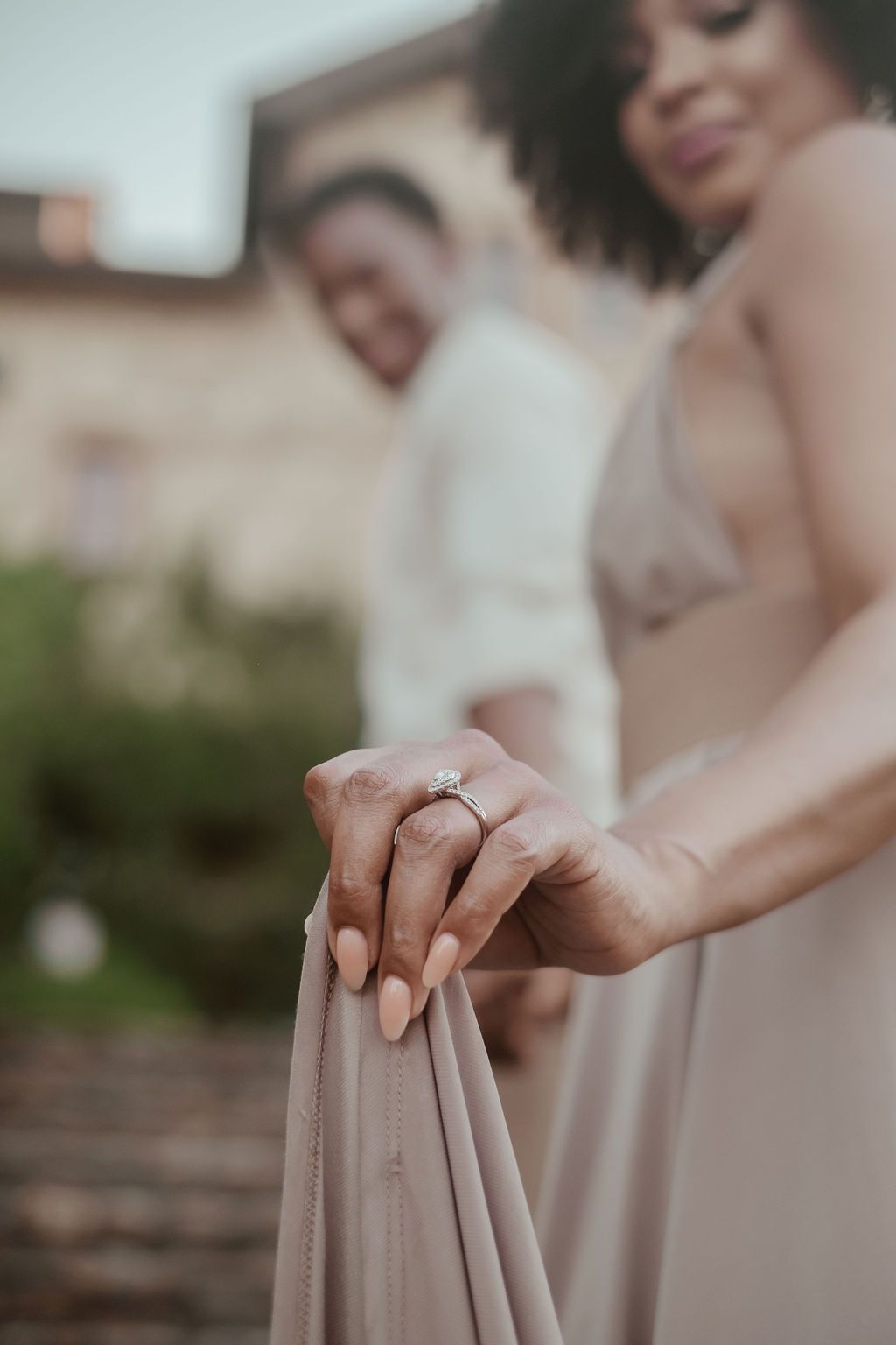 Close-up of a Black bride\u2019s hand holding her dress hem, showcasing her diamond engagement ring.